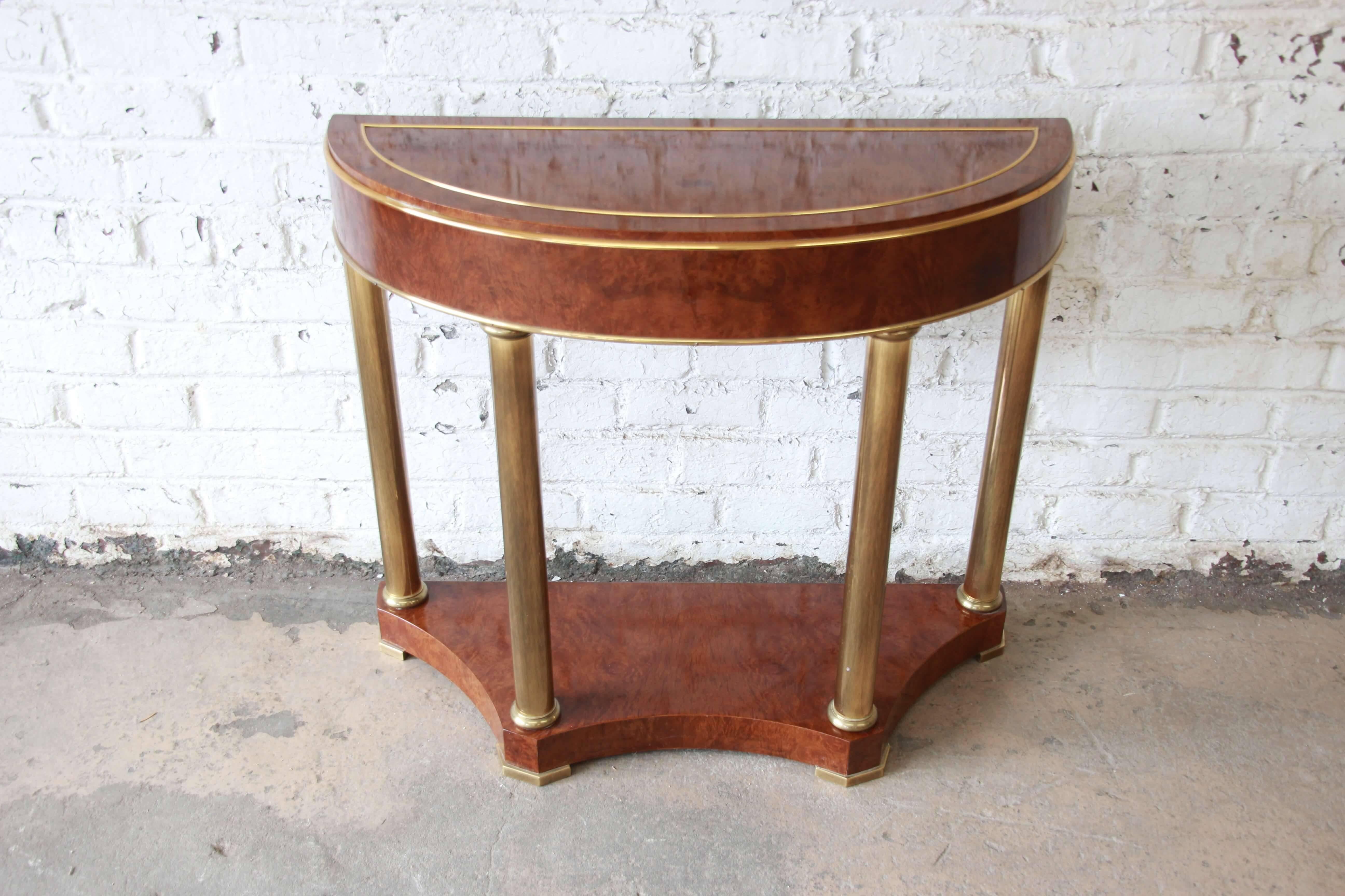 Offering a beautiful burl wood and brass demilune console table by Mastercraft. The table has brass columns and trim with a stunning burl wood finish. The feet of the demilune table are solid brass and the piece is in overall great vintage condition.