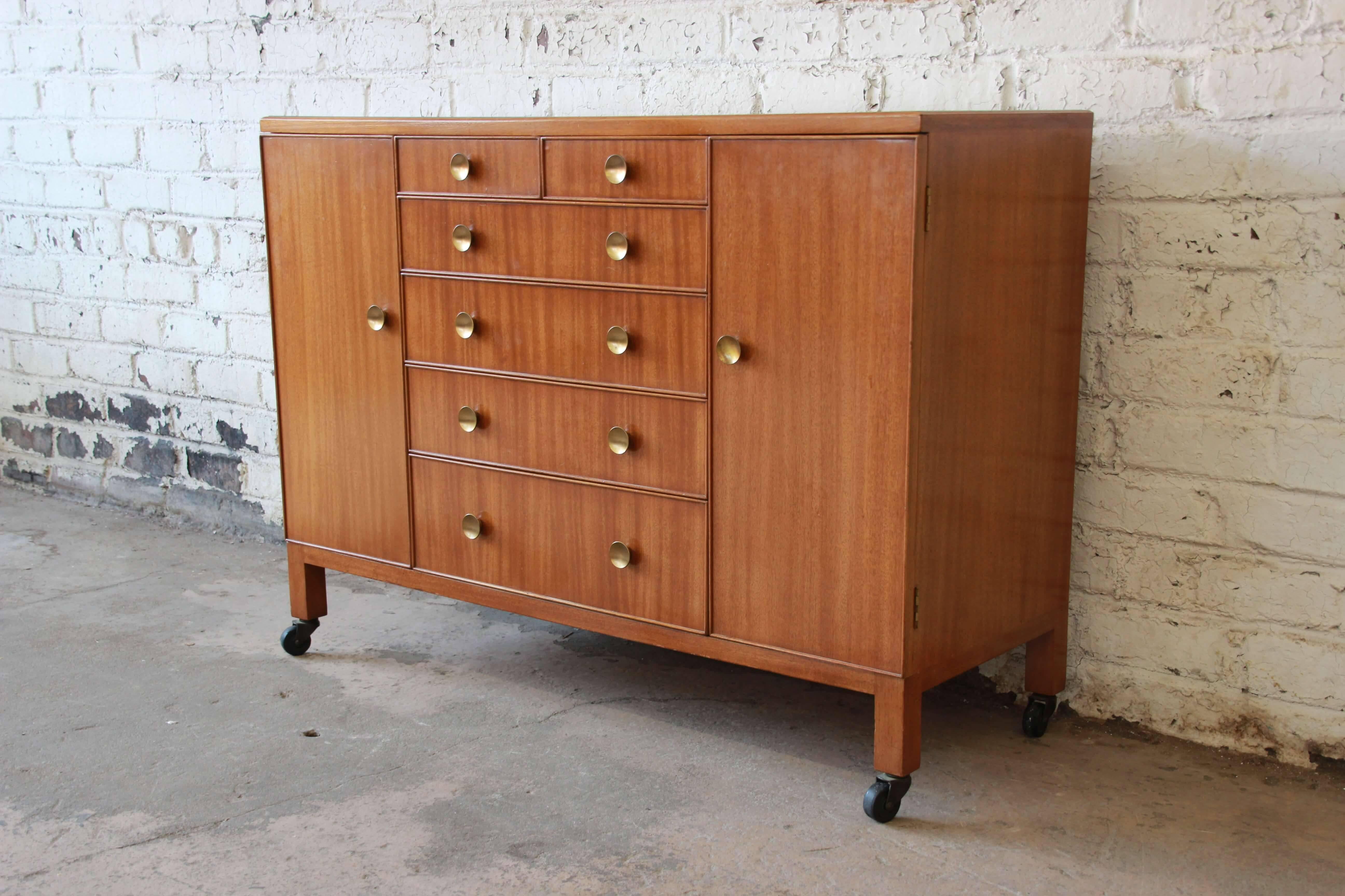 Offering an exceptional early Edward Wormley for Dunbar long dresser. This piece has its original brass circular pulls and an inset glass top. The dresser is made from solid mahogany and features six drawers and two cabinets. Behind each cabinet are