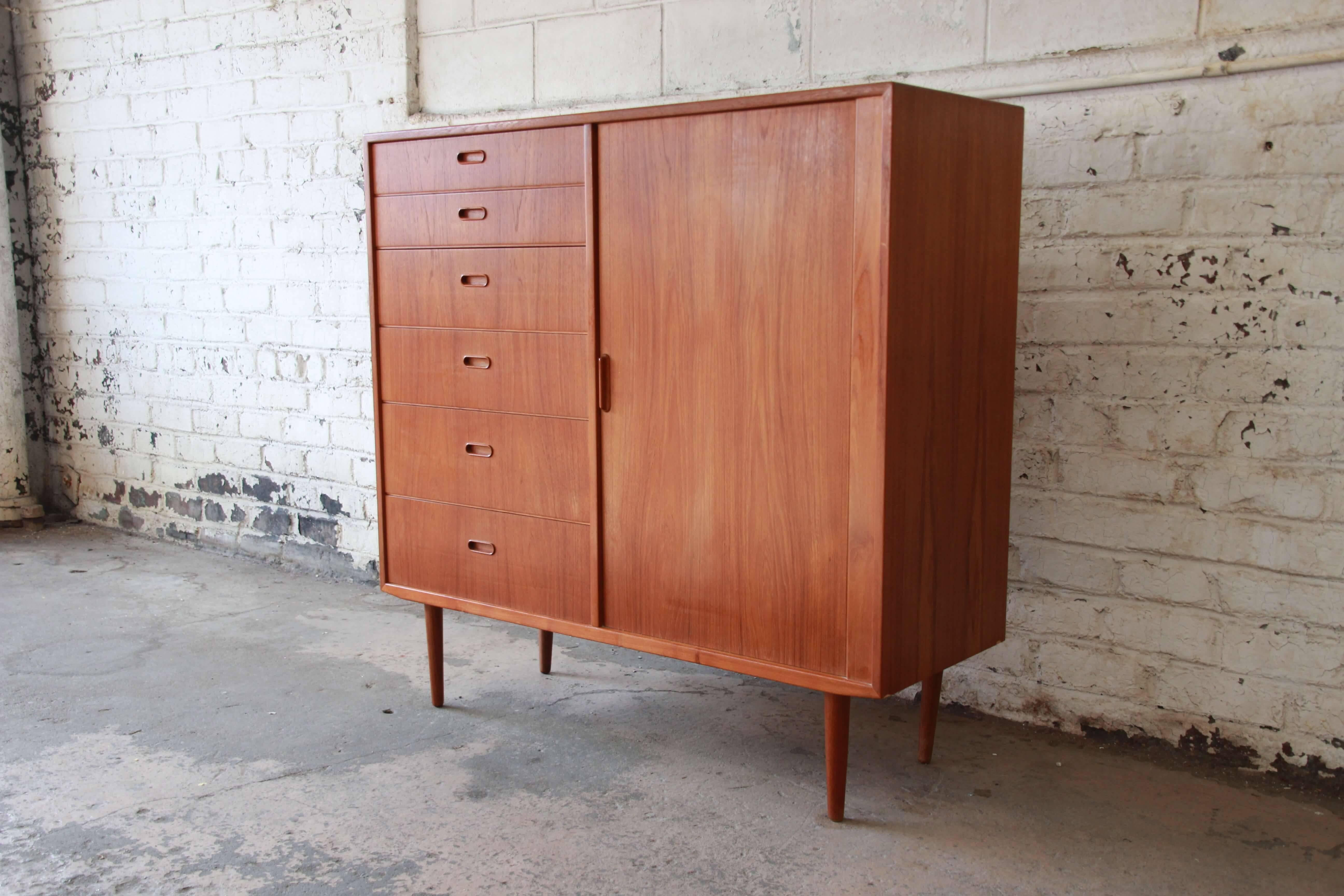 Offering a fantastic Danish modern teak gentlemen's chest by Falster of Denmark. This stunning chest offers six graduated drawers on the left side with nice sculpted pulls. The right side has a smooth sliding tambour door that open up to six