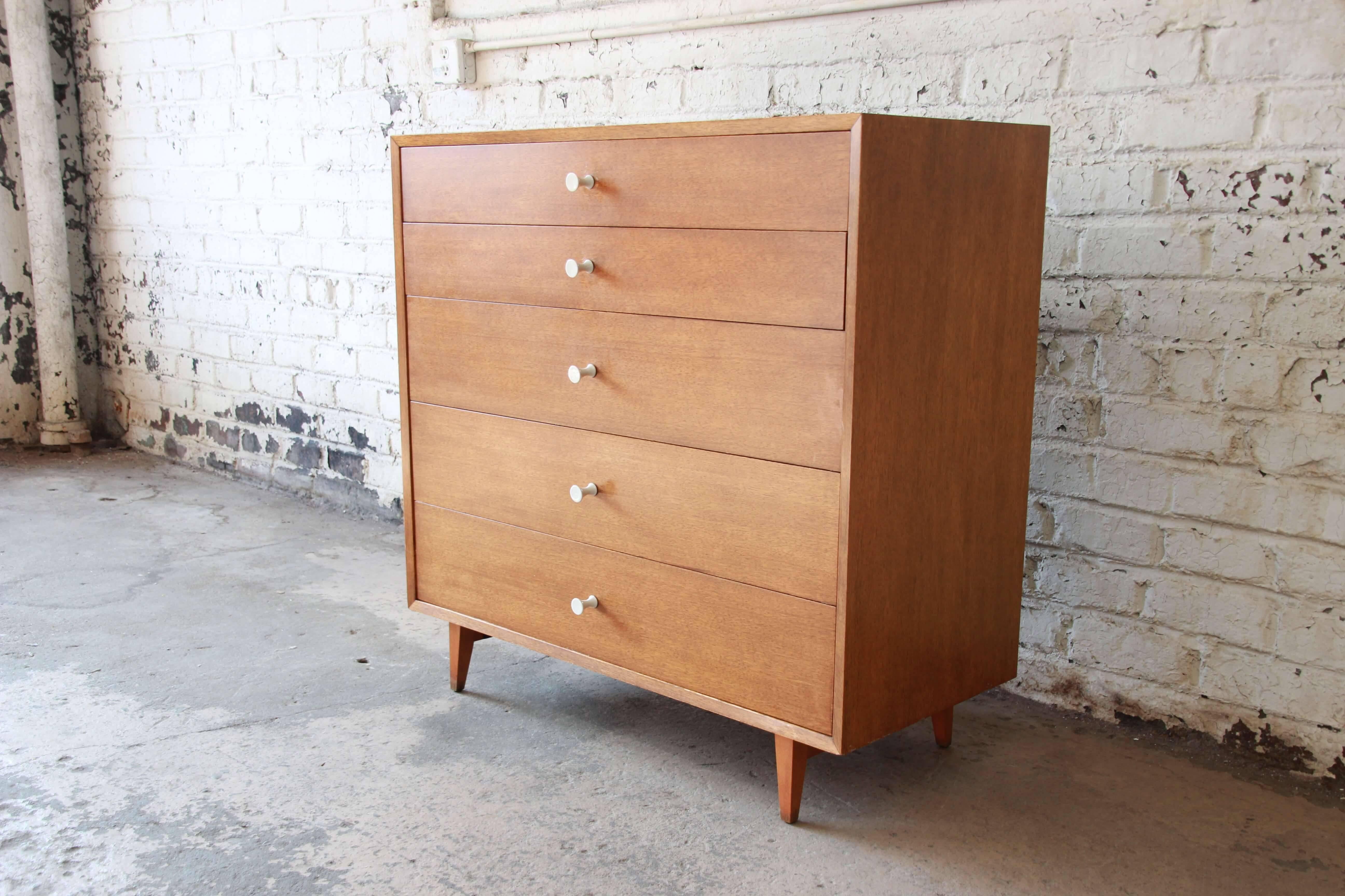 Offering a gorgeous mid-century modern highboy dresser designed by George Nelson for Herman Miller. The dresser features five graduated drawers that open and close smoothly with original porcelain pulls. The mahogany dresser has clean modern lines