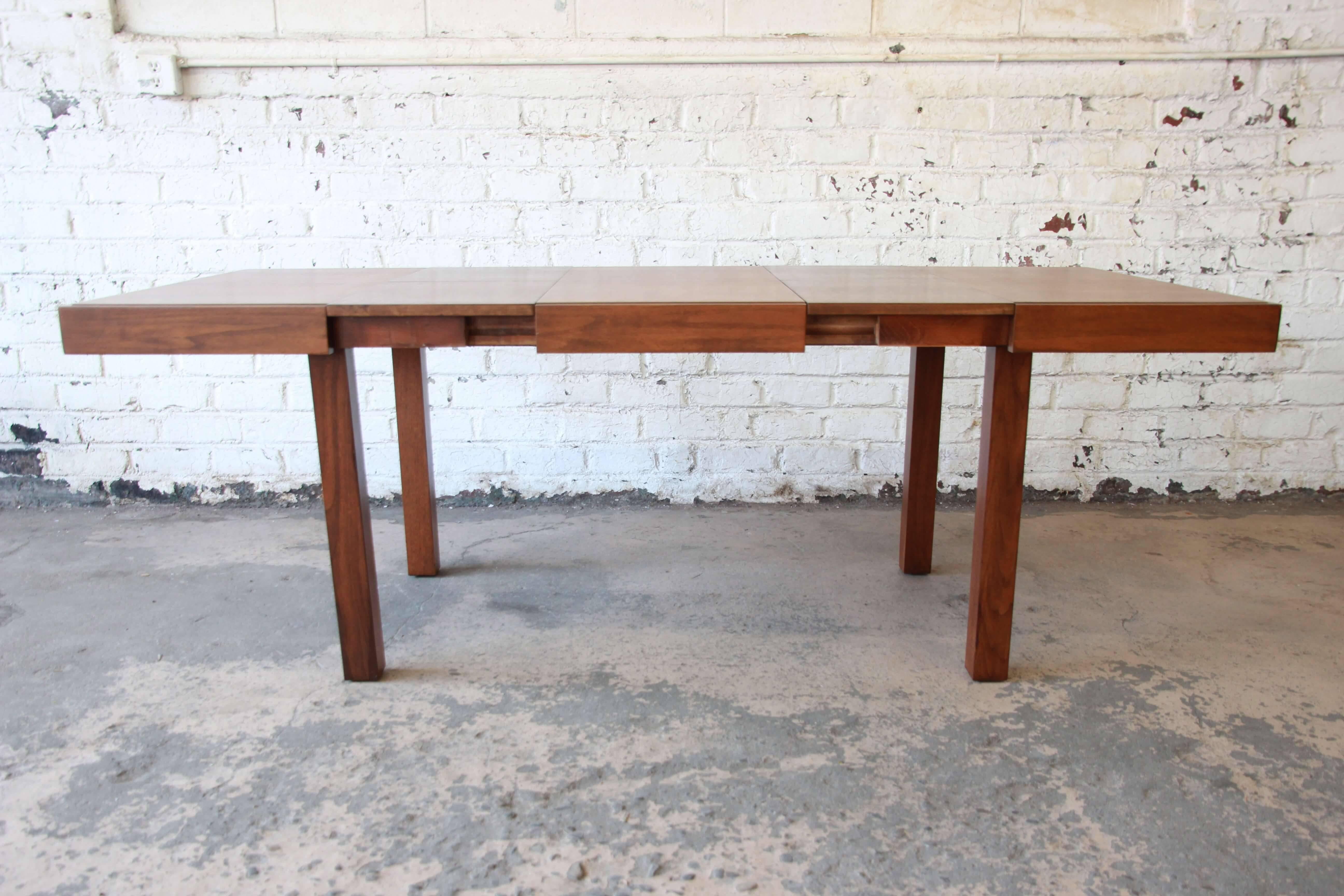 Offering a very nice and refinished extension dining table by George Nelson for Herman Miller. This earlier work of Nelson's has clean geometric lines with a beautiful walnut wood grain. There are two leaves that are stored inside the table and are