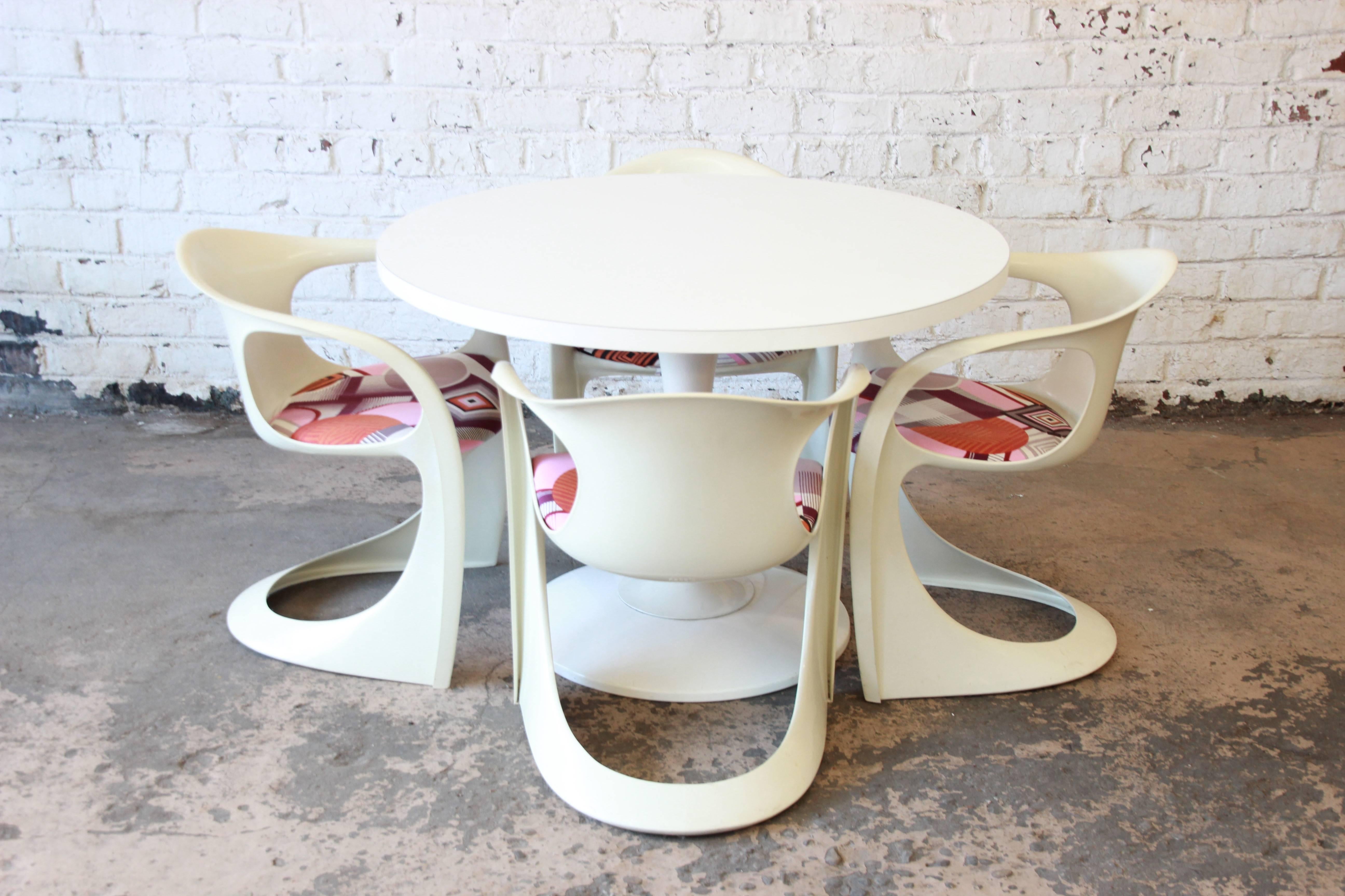 A stylish Casalino tulip dining set designed by Alexander Begge for Casala. The set includes a round tulip table and four chairs. The chairs are made of a molded white polystyrene. The seats are upholstered in a vintage geometric patterned fabric.