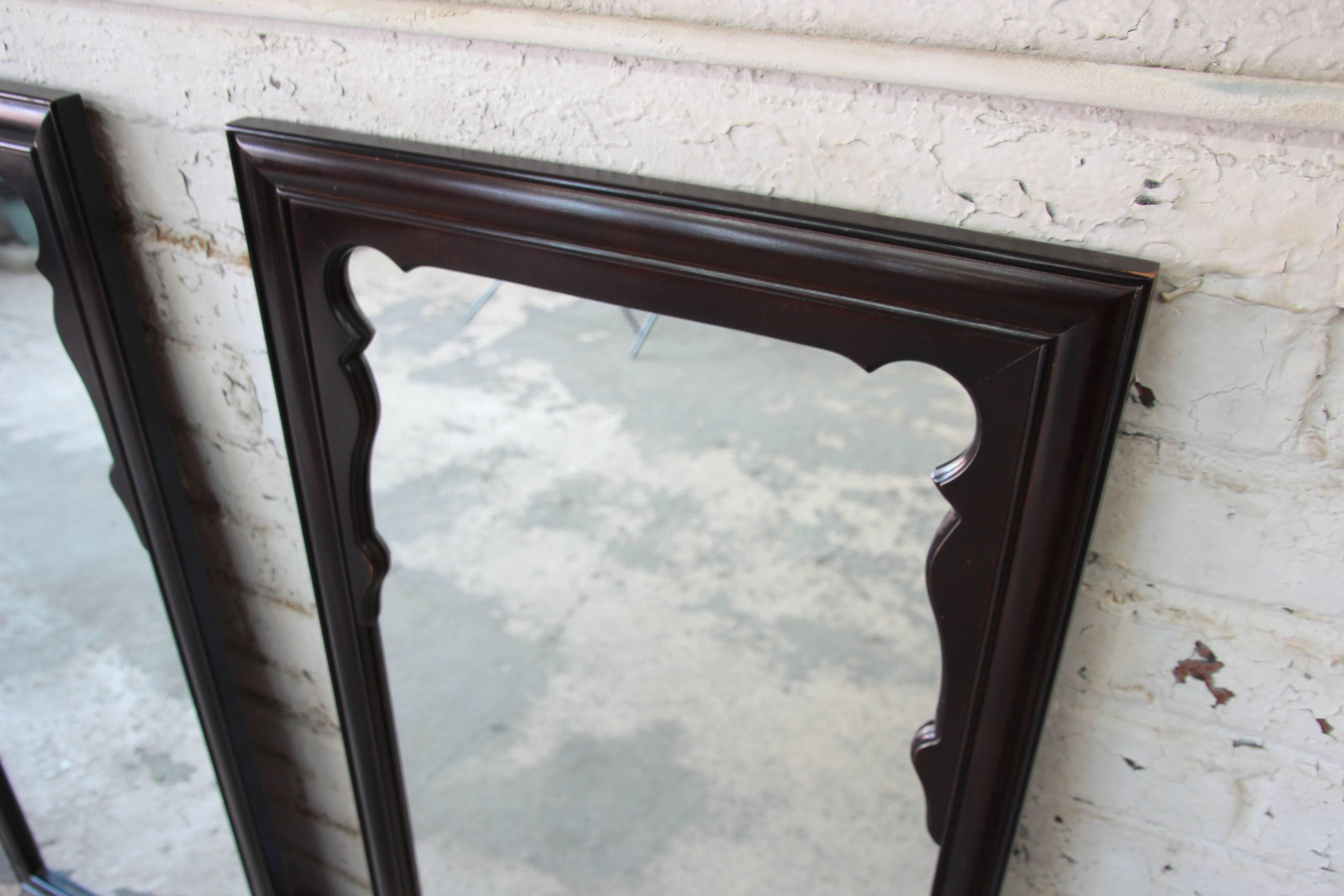 A beautiful pair of midcentury chinoiserie mirrors. The mirrors feature solid wood frames in a dark brown lacquer, with subtle Asian design. The mirrors are from the Chin Hua collection by Century Furniture. They are in very good original condition,