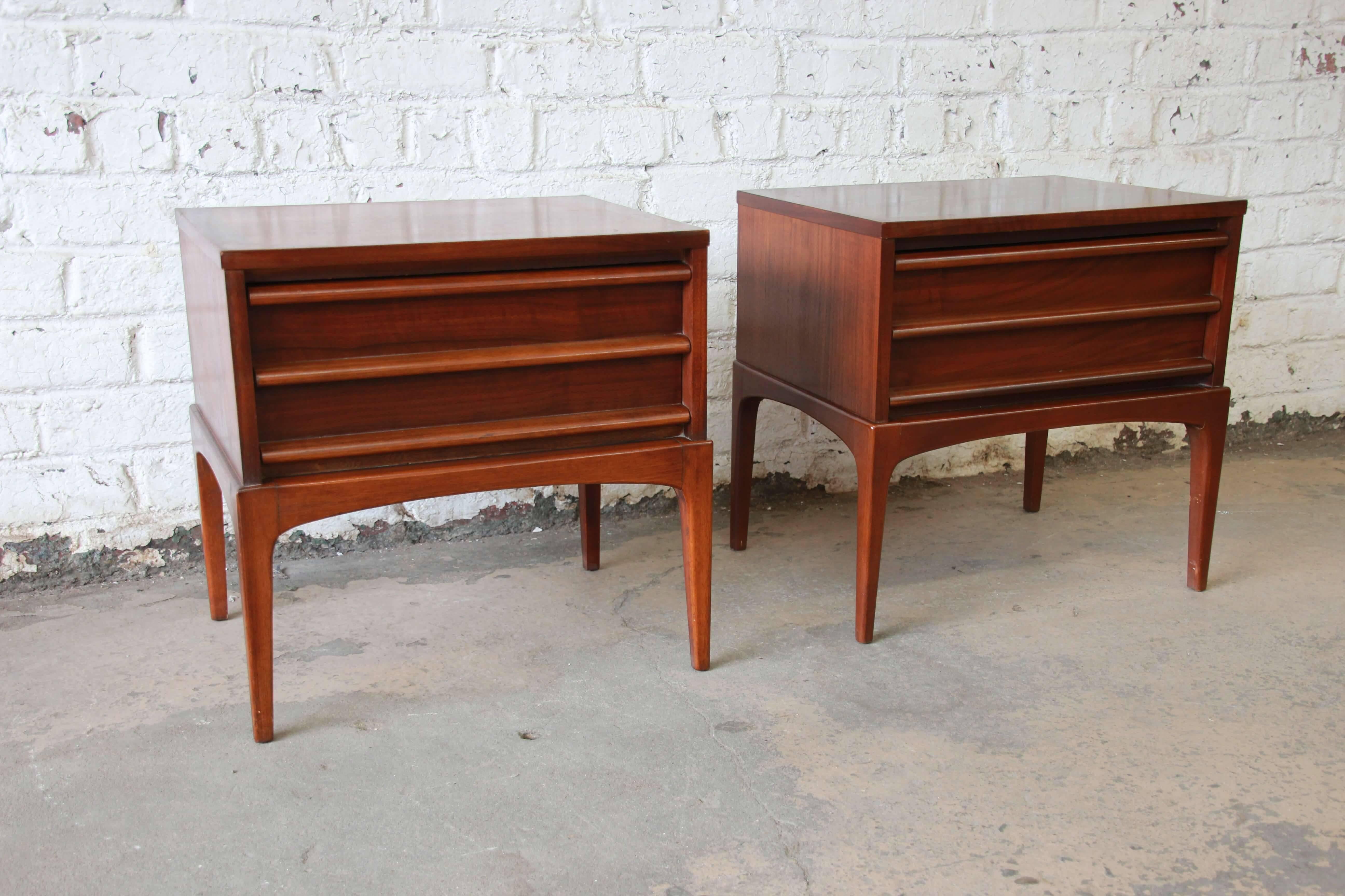 Offering a very nice pair of Lane Rhythm Mid-Century Modern sculpted walnut nightstands. The nightstands have a beautiful walnut wood grain with round sculpted pulls. Each Stand offers a nice smooth sliding drawer that offers lots of room for