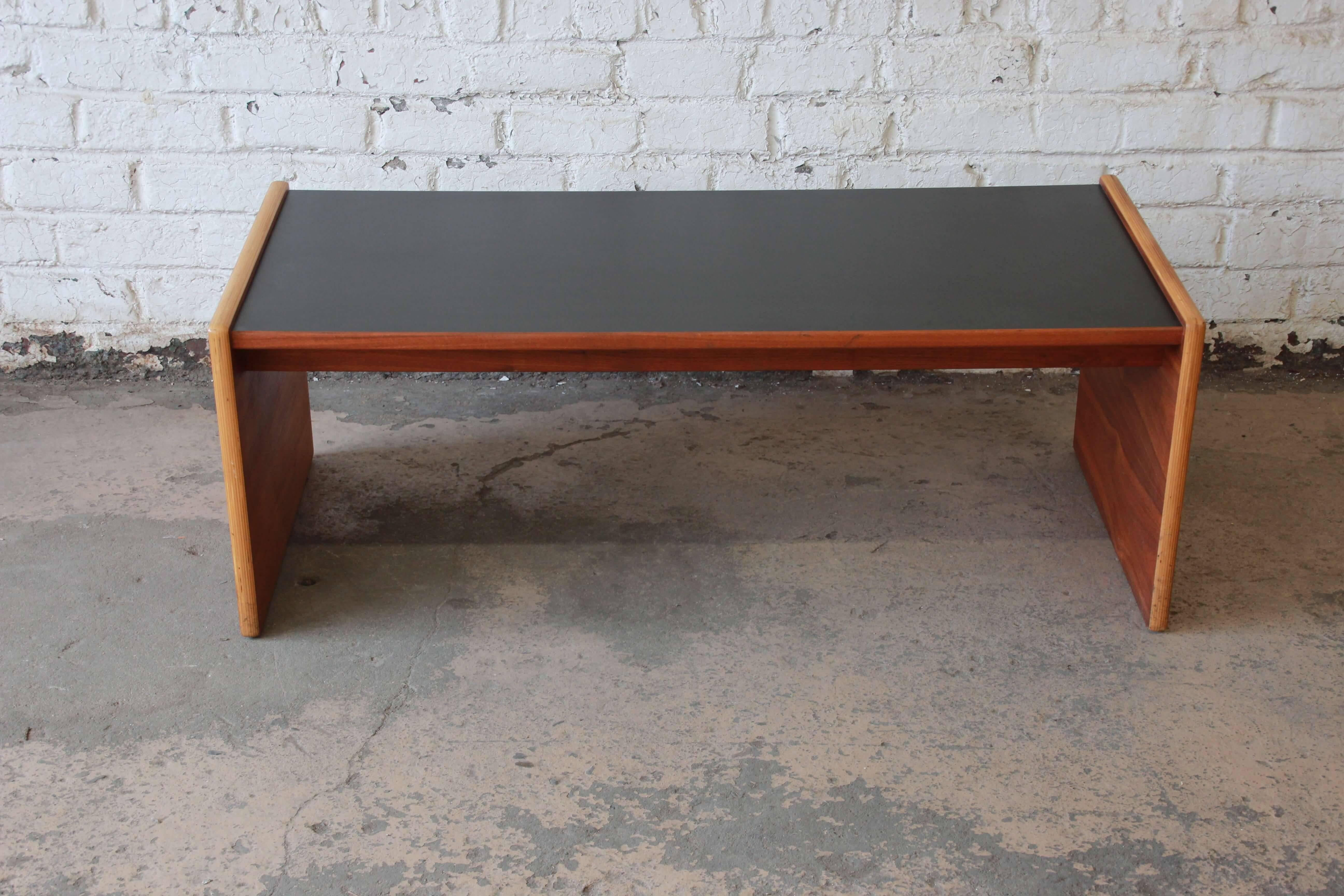 Offering a very nice and stylish Mid-Century Modern coffee table or bench by Jens Risom. The bench features a beautiful walnut wood grain on the legs that connect to a durable black laminate top. The table is in great vintage condition and is solid