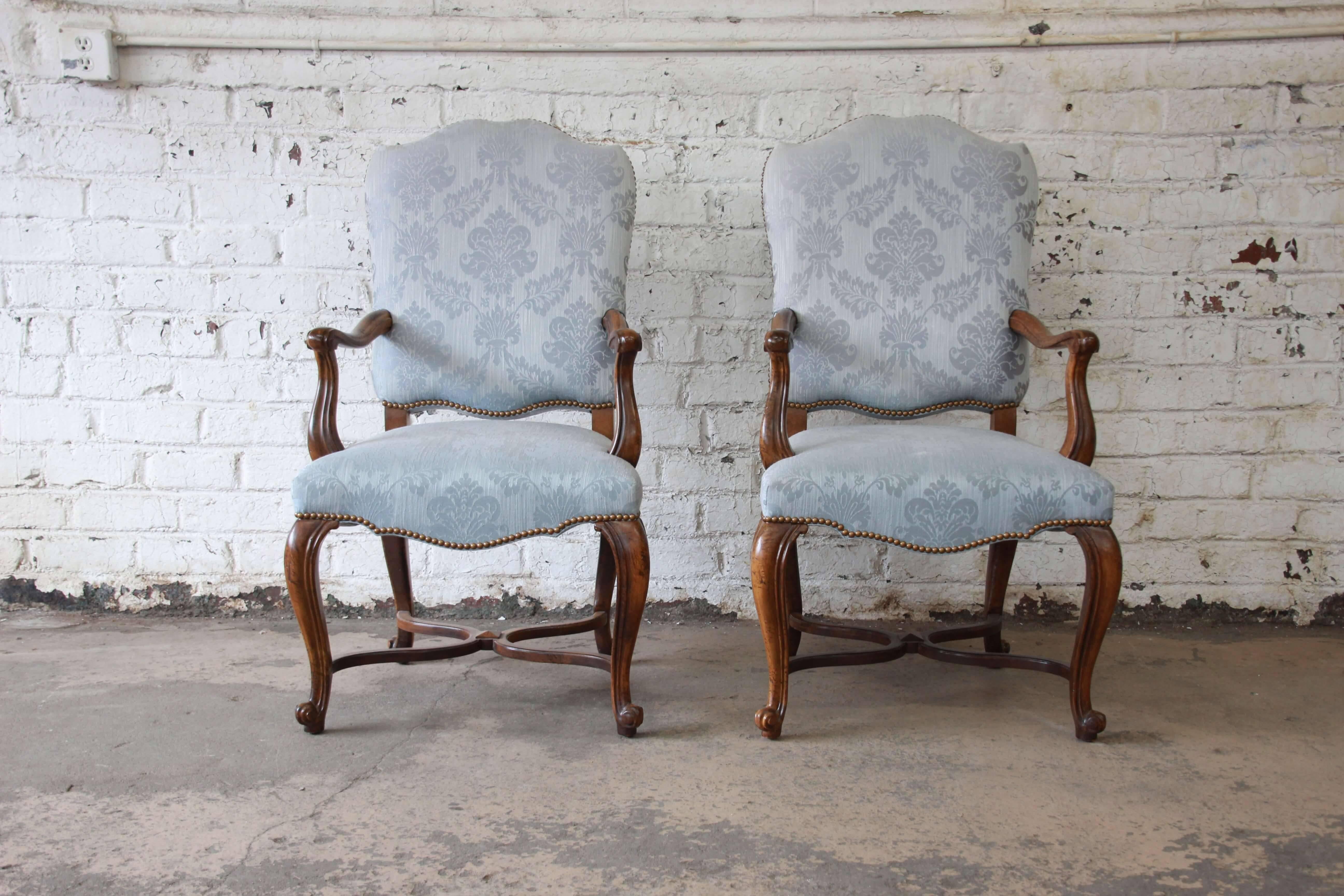Offering a rare and exceptional set of 12 French Provincial dining chairs by Baker Furniture. These beautiful chairs feature a blue upholstery that is clean with no tears. The set includes two large captains chairs and ten side chairs. Each chair is