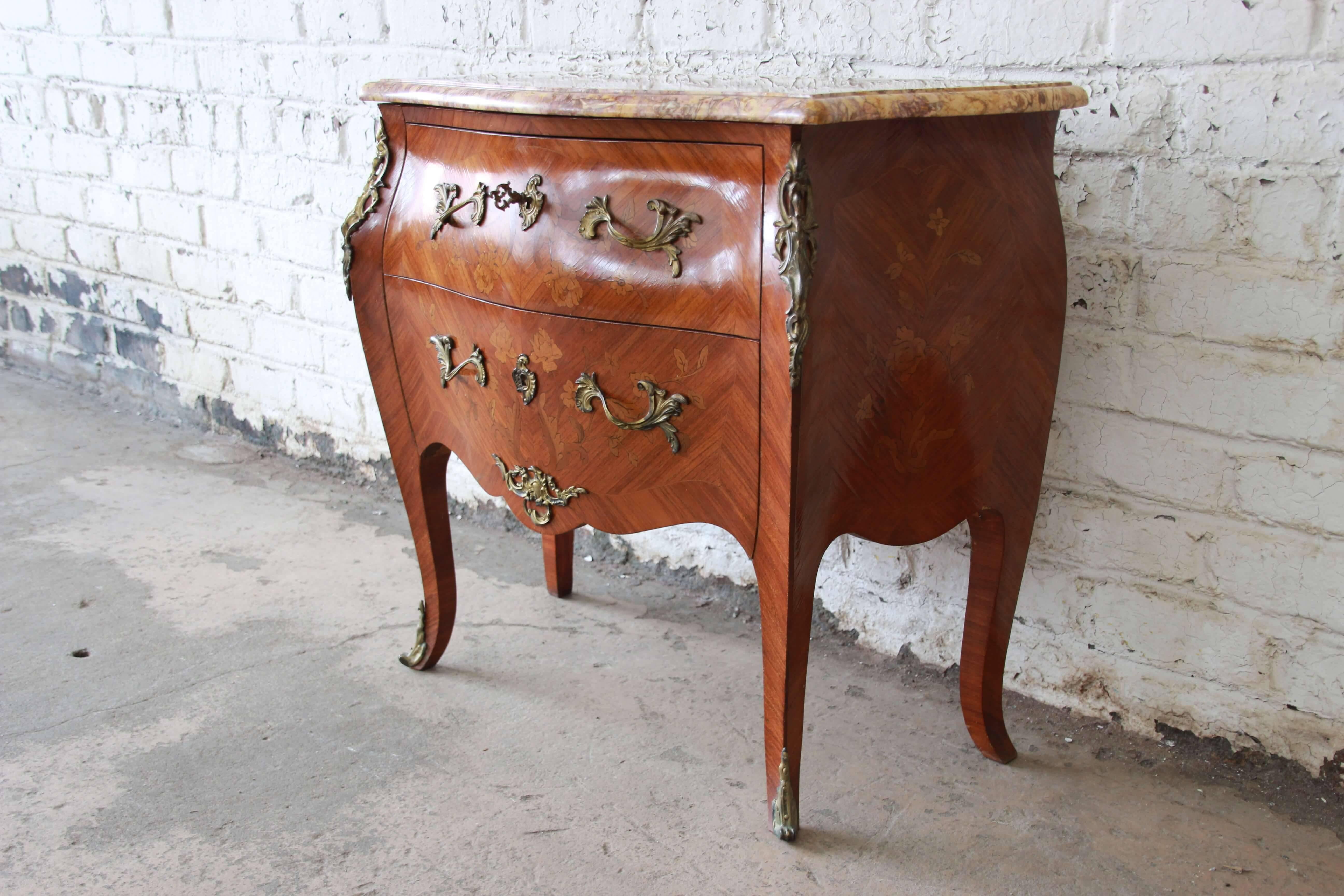 Offering a very nice French marble-top inlaid Bombay chest. The chest has two large drawers that offer plenty of storage with beautiful floral inlays and bronze ormolu. This beautiful design continues throughout the piece and has a nice marble top.