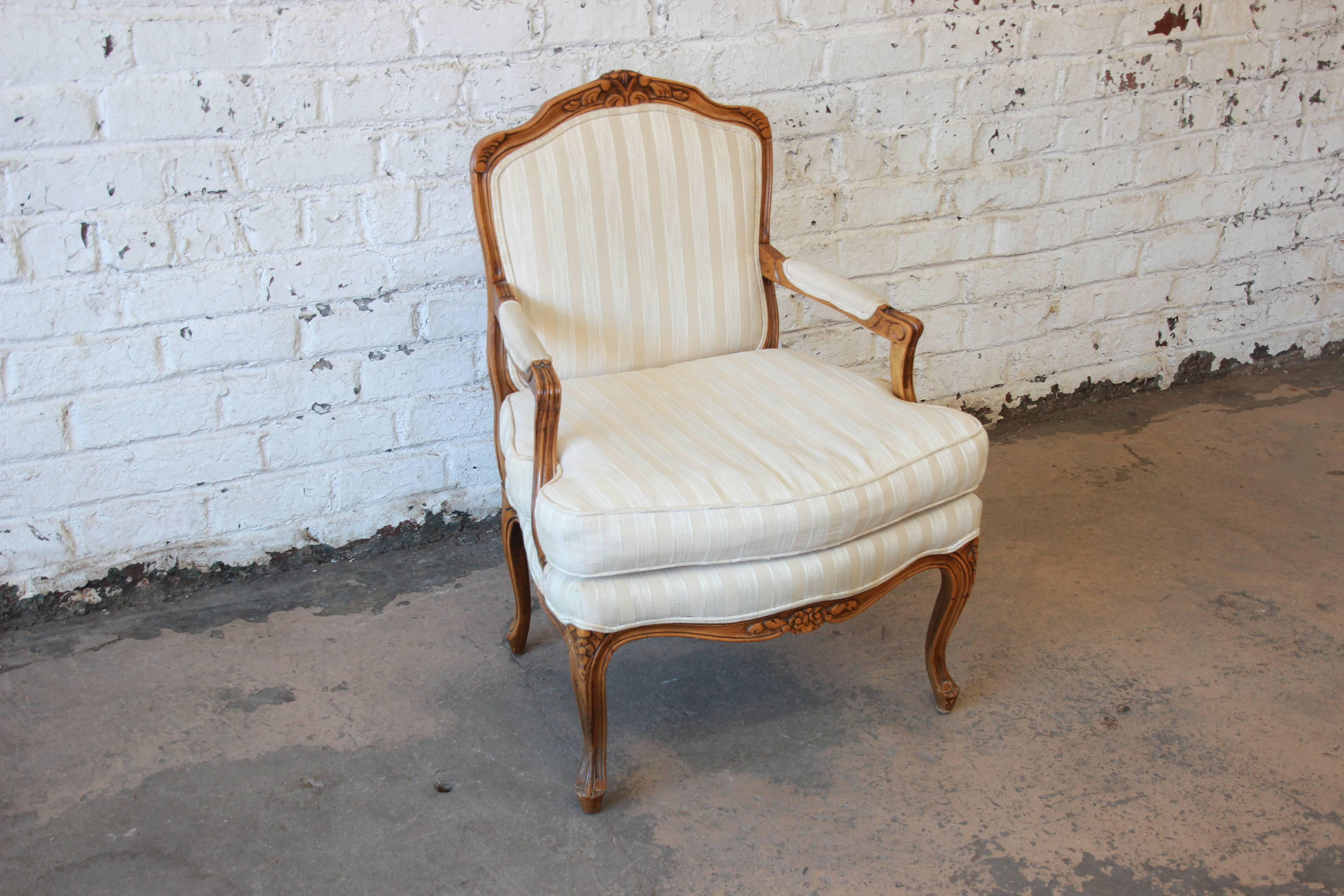 Offering a very nice Baker furniture French armchair. The chairs has a nice professionally cleaned Ivory upholstery. The chair is solid and sturdy with French carved details. It is comfortable and manufactured by Baker Furniture. Very minor wear