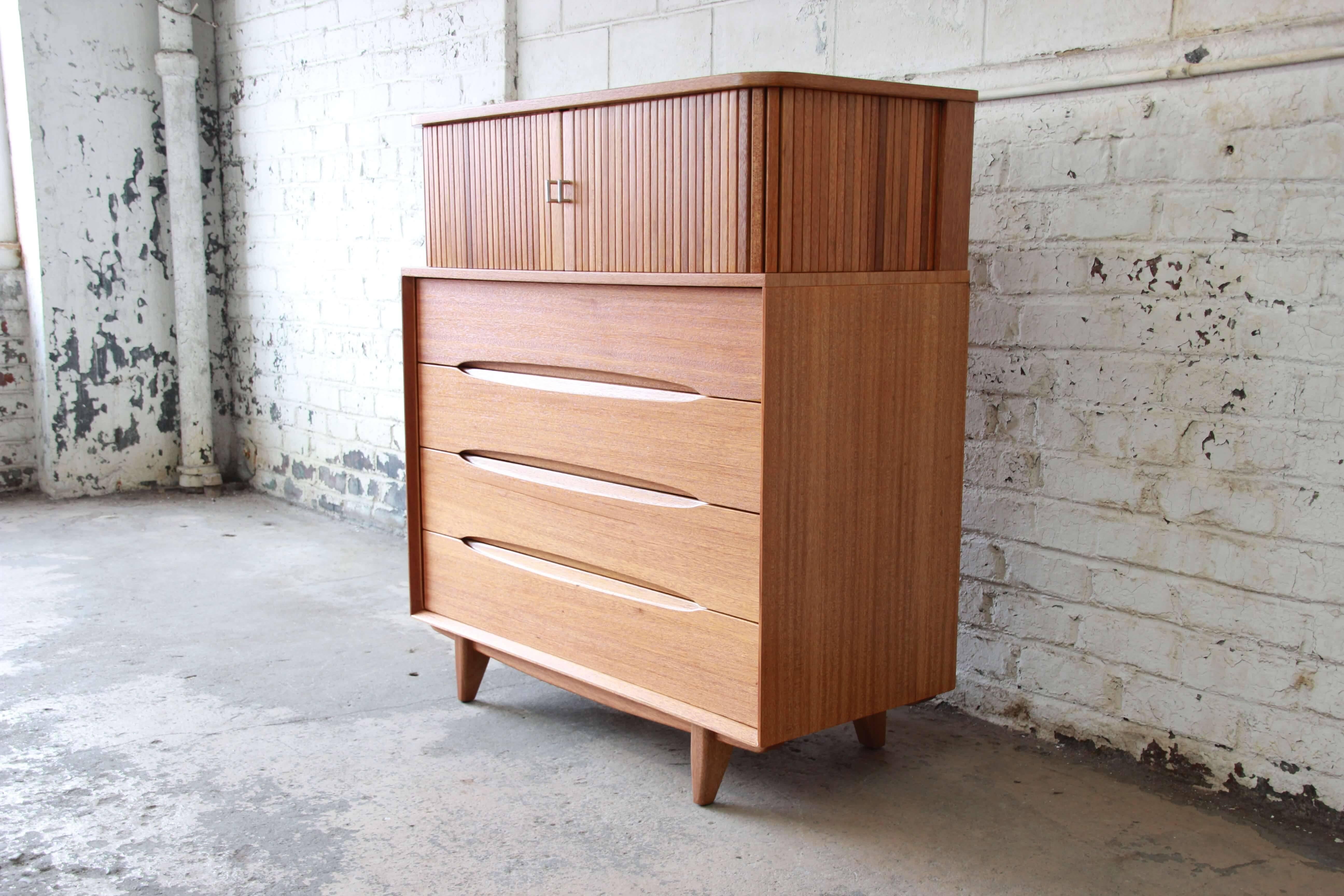 Offering an exceptional Mid-Century Modern ten-drawer tambour door highboy dresser designed by Paul Laszlo for Brown Saltman. The dresser features gorgeous mahogany wood grain, sculpted drawer pulls, and sleek midcentury design. Behind the tambour
