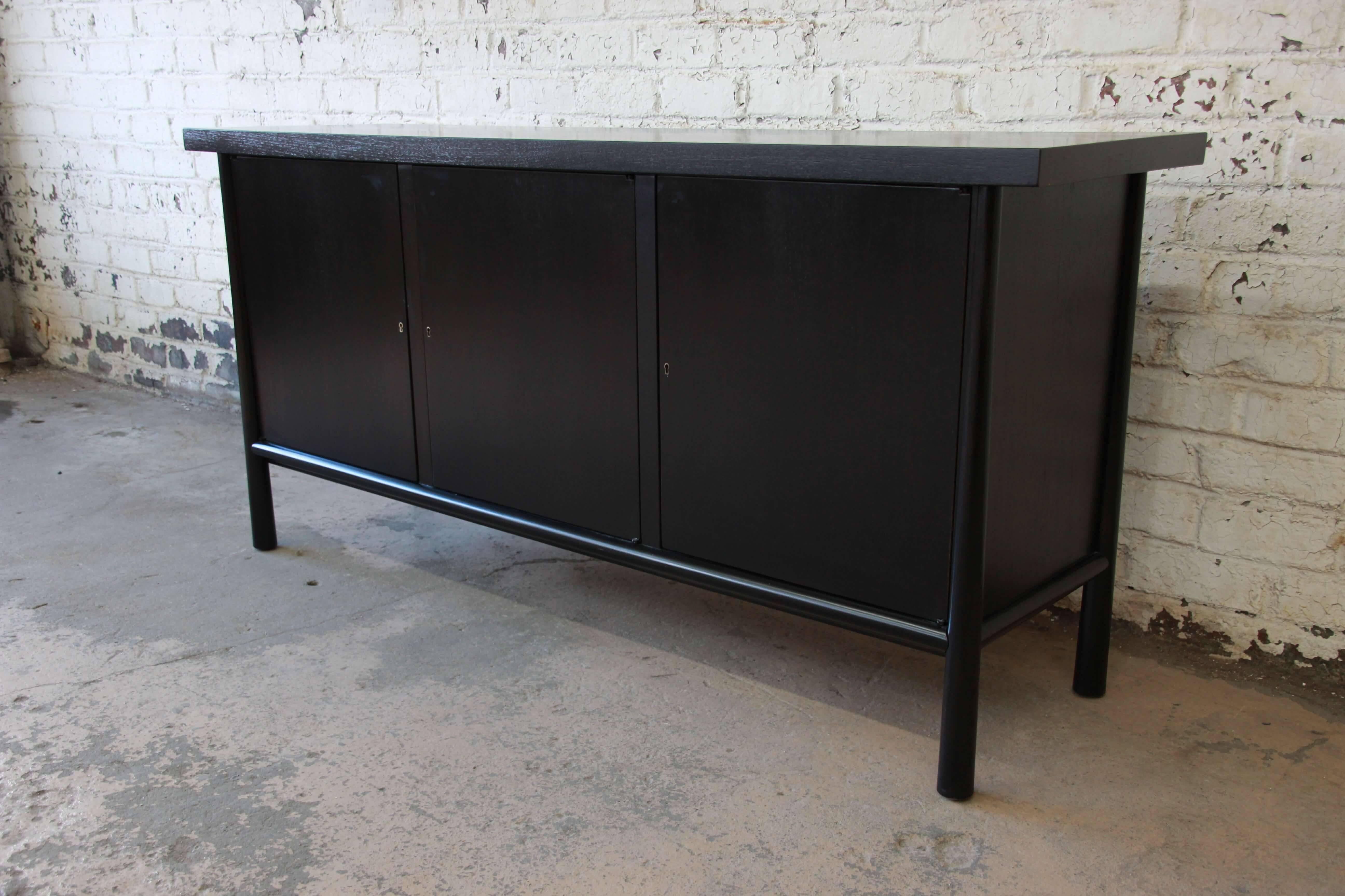 Offering a very nice and newly ebonized sideboard credenza by T.H. Robsjohn Gibbings for Widdicomb. This exquisite piece has three front cabinet doors that come with the locking key. The centre door opens to four smooth sliding drawer. The left and