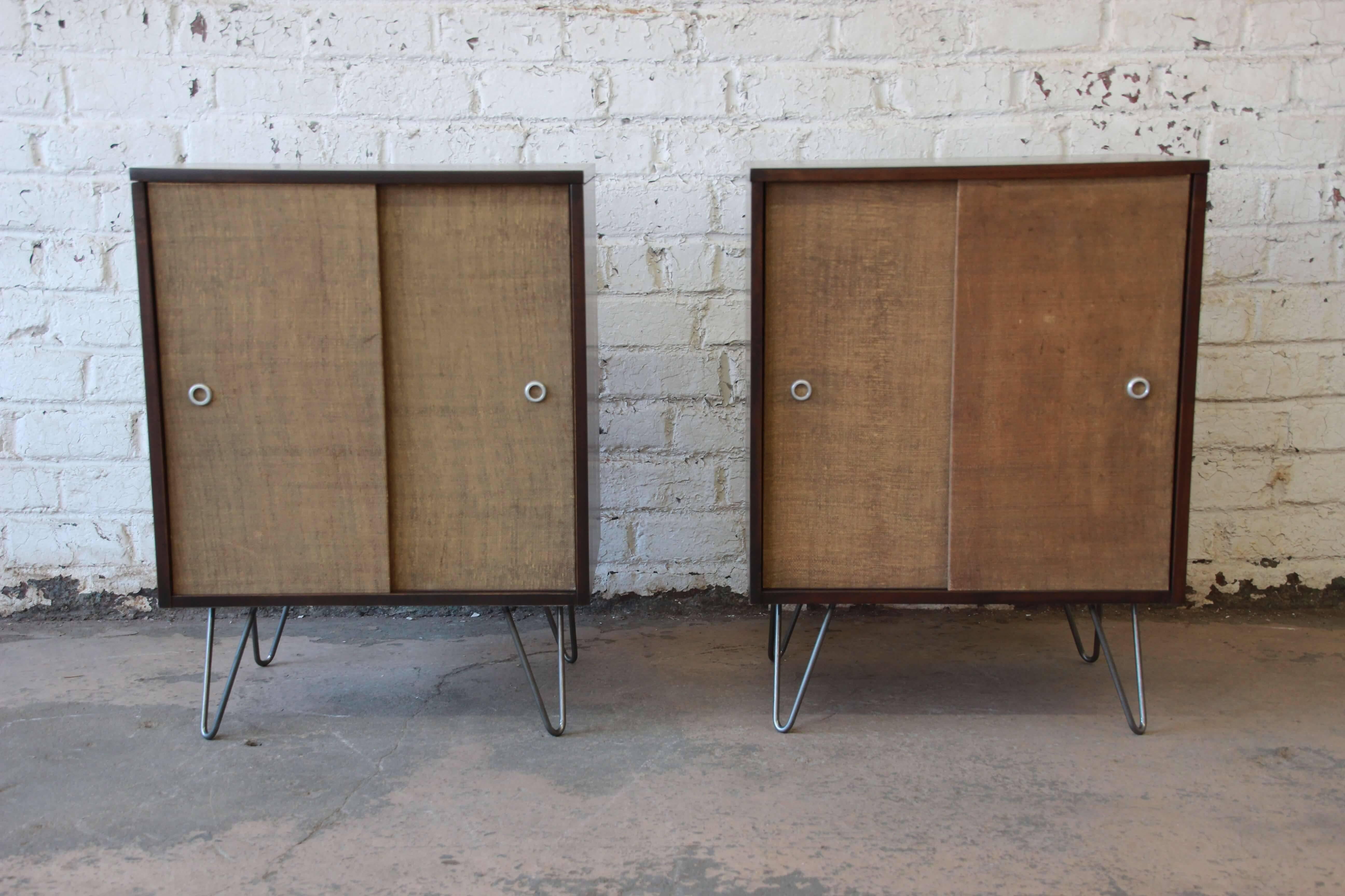 Offering a very nice pair of Paul McCobb for Planner Group cabinets on hairpin legs. The cabinet serve nicely as night stands or end tables. Each have the original canvas front sliding cabinet doors with aluminium pulls. They open up to a nice