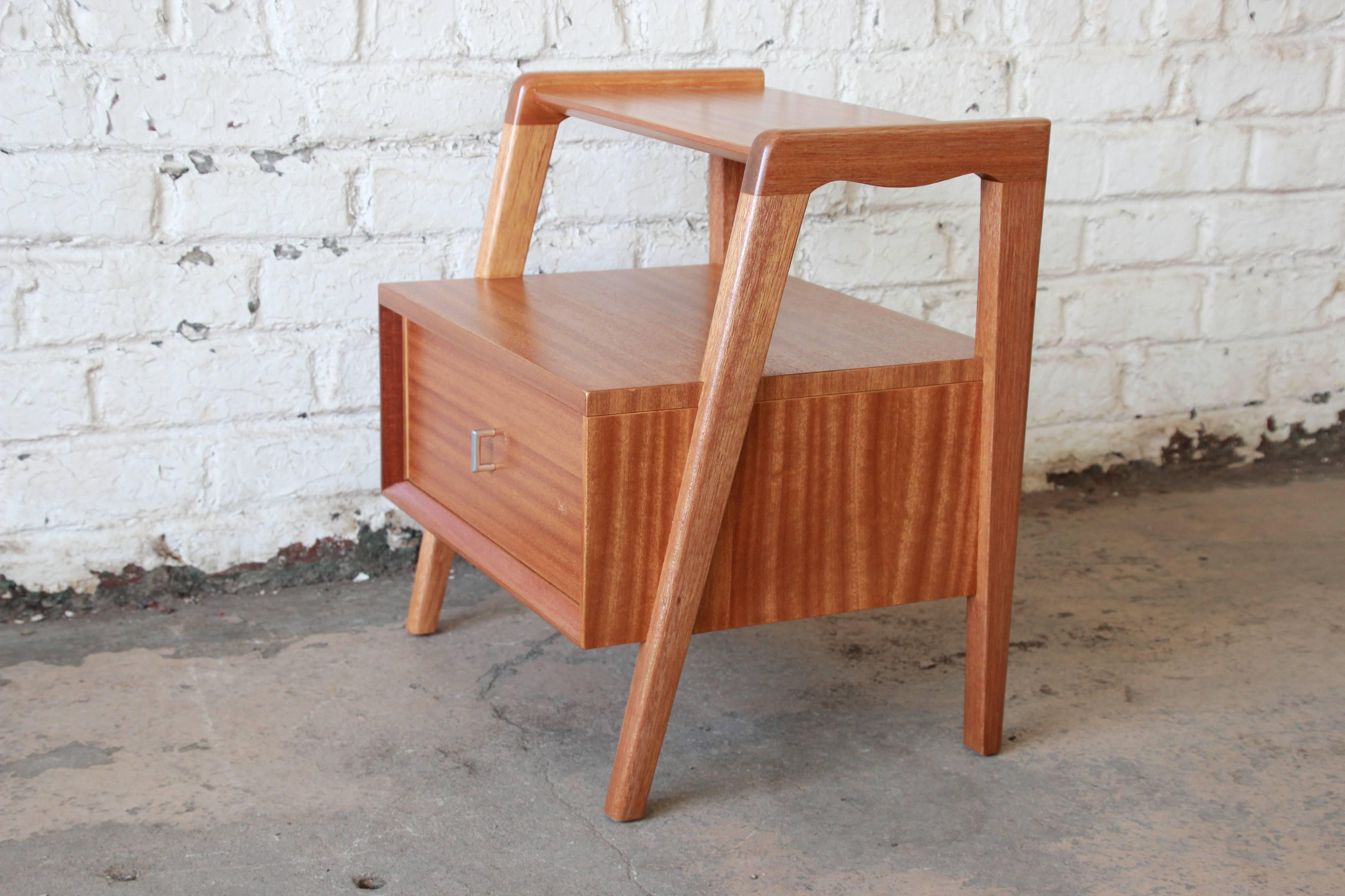 An exceptional Mid-Century Modern mahogany nightstand or end table designed by Paul Laszlo for Brown Saltman. The nightstand features gorgeous mahogany wood grain and sleek midcentury design. It has one deep dovetailed drawer, and the original Brown