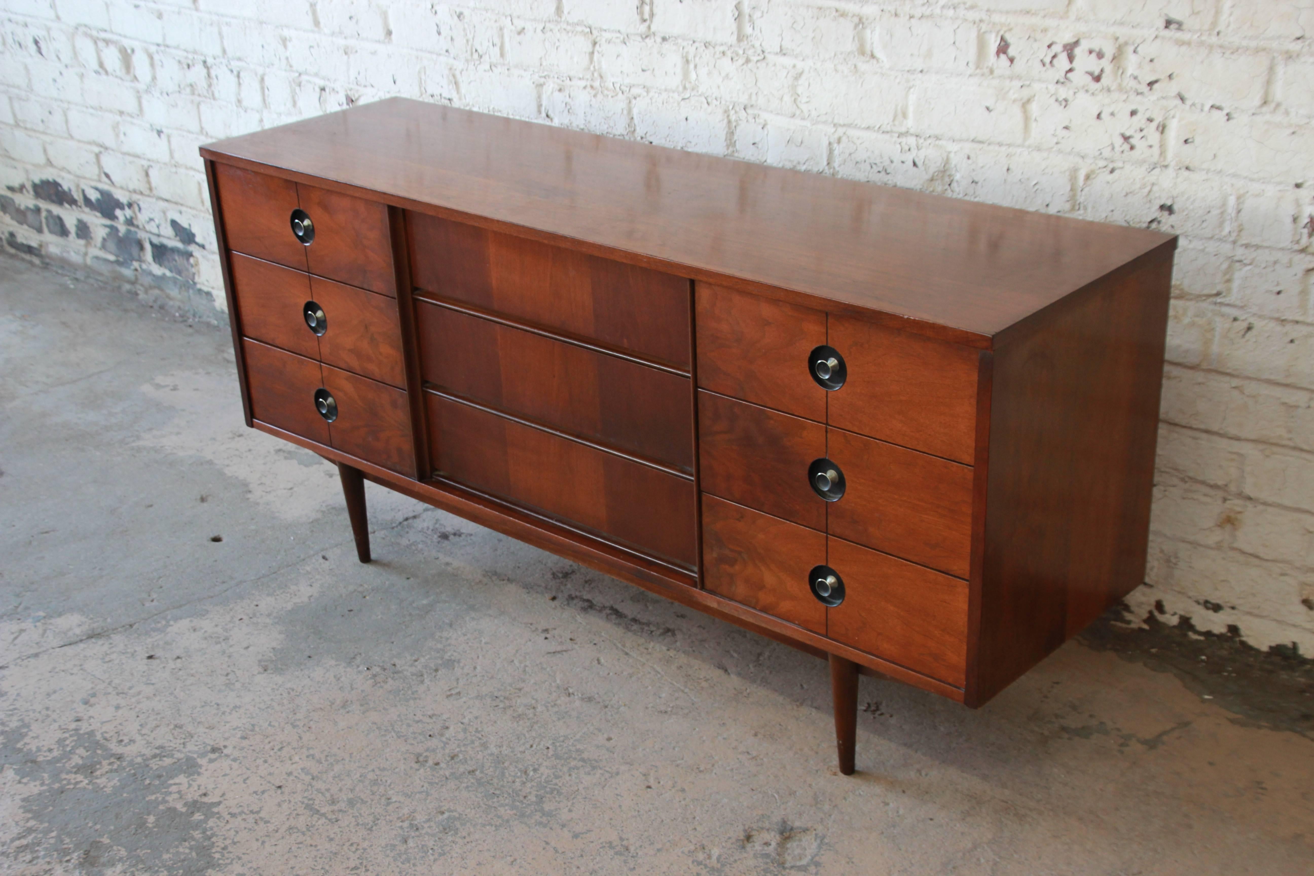 Offering a very nice Mid-Century Modern triple dresser or credenza from the Finnline Collection by Stanley Furniture. The credenza features gorgeous walnut wood grain and sleek mid-century lines. It offers ample room for storage, with nine deep