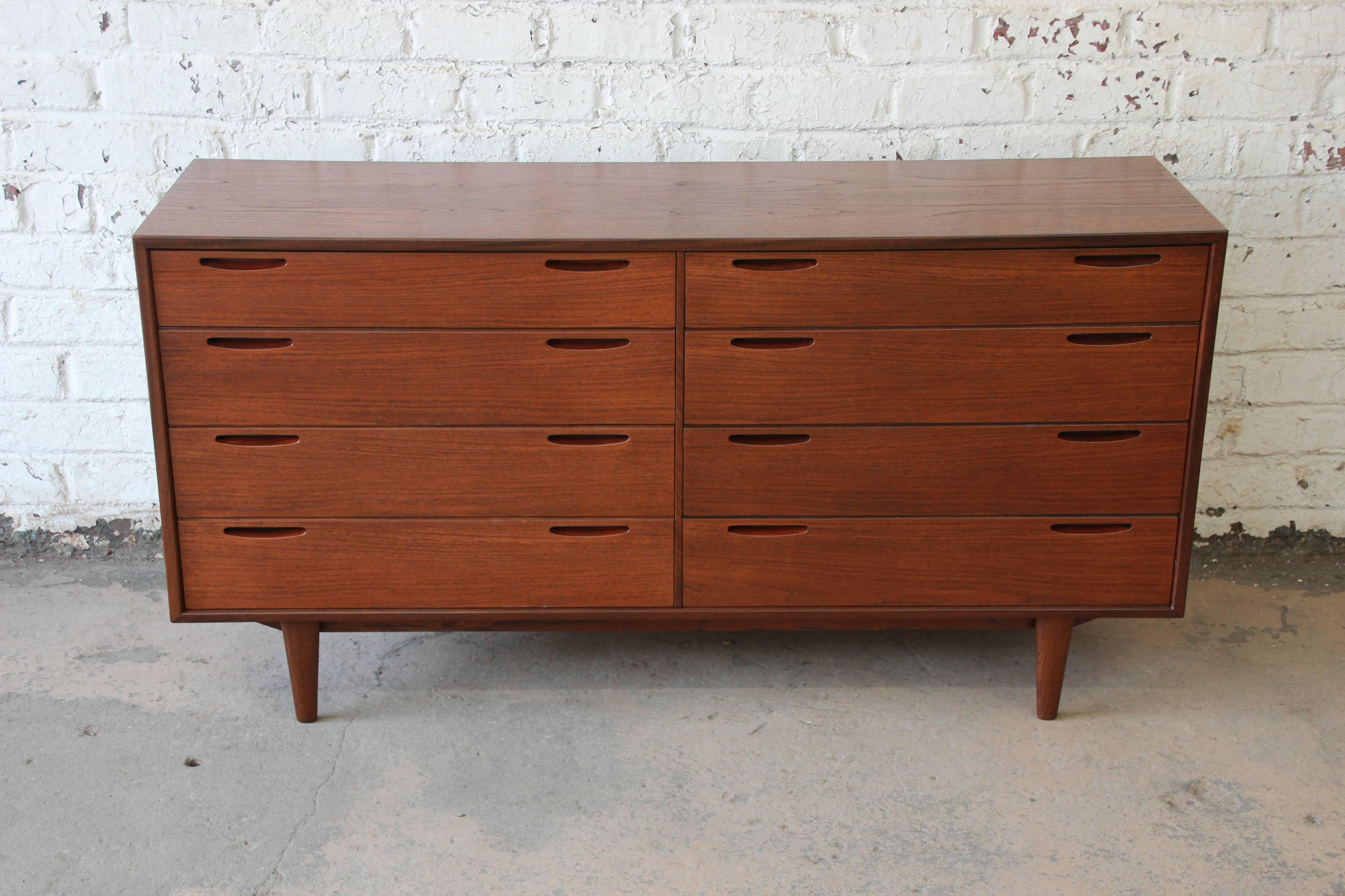 An exceptional 1950s Danish modern teak eight-drawer dresser or credenza. The dresser features gorgeous teak wood grain and sleek Danish Modern design. It offers ample room for storage with eight drawers, each with minimalist inset pulls. The
