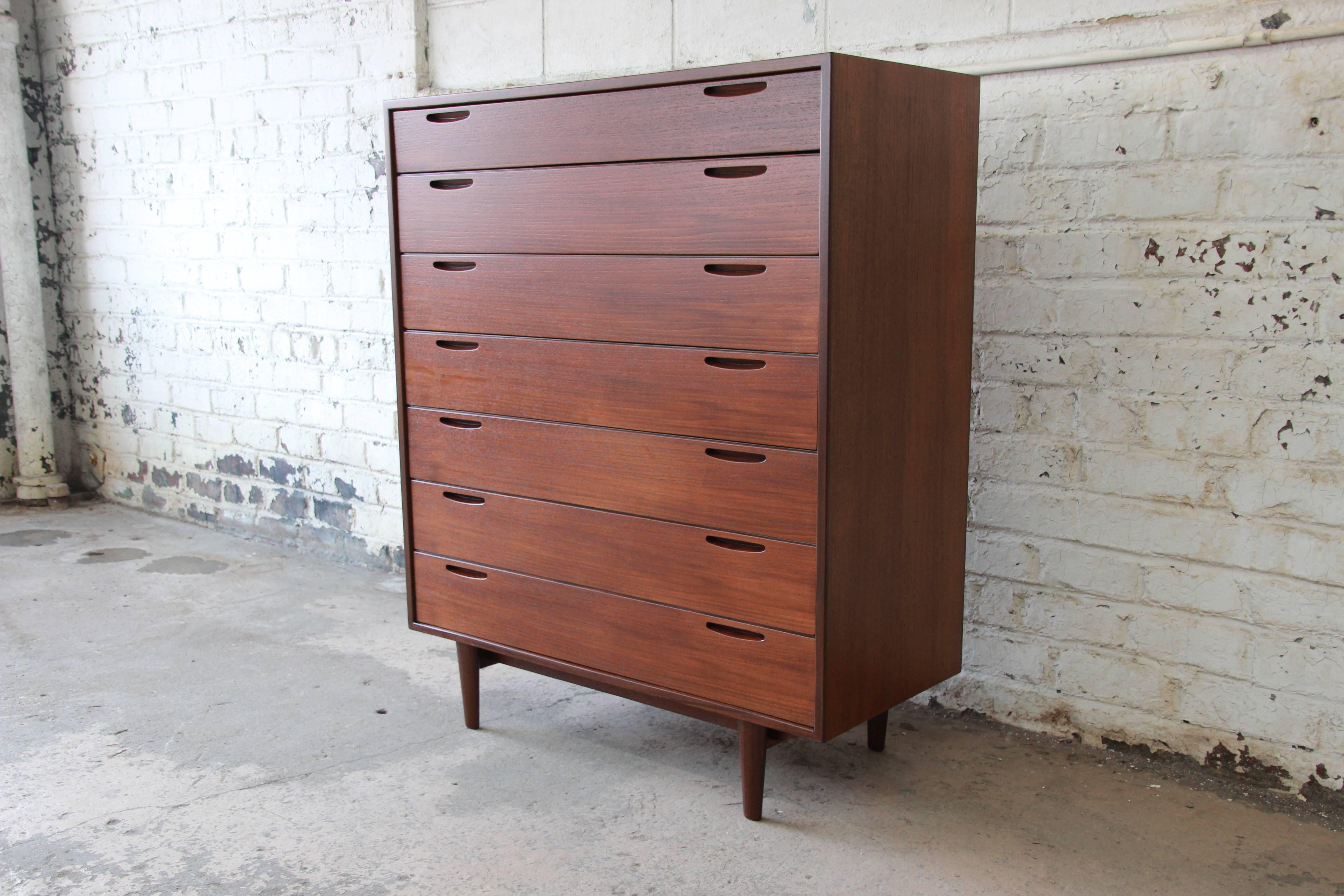 An exceptional 1950s Danish modern teak seven-drawer highboy dresser. The dresser features gorgeous teak wood grain and sleek Danish modern design. It offers ample room for storage with seven drawers, each with Minimalist inset pulls. The dresser is