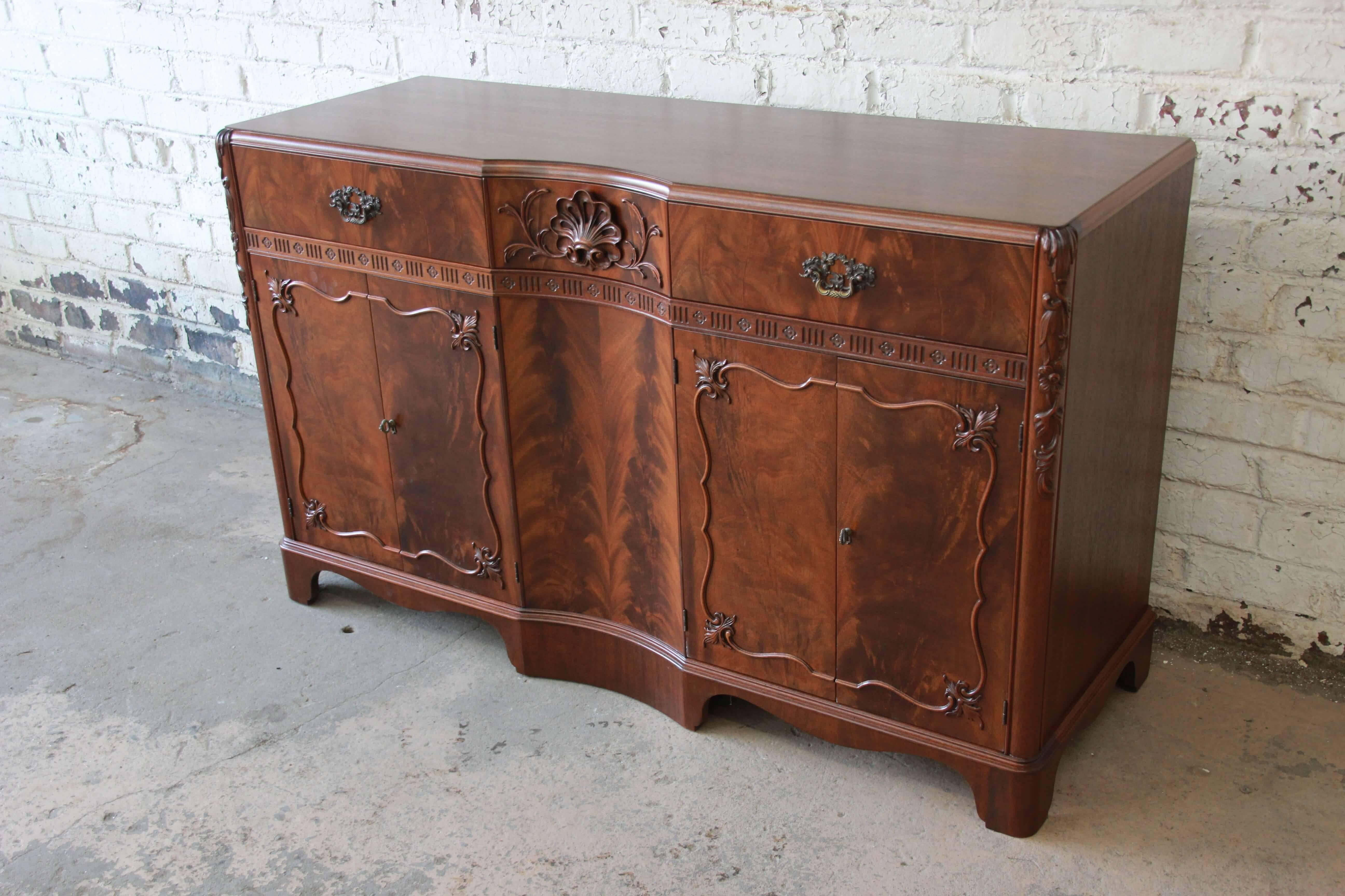 Offering a very beautiful French carved flamed walnut sideboard by Landstrom. This piece has statement making wood grain with fine carved details. There are three drawers at the top, one with a French carved pull. The left portion of the sideboard