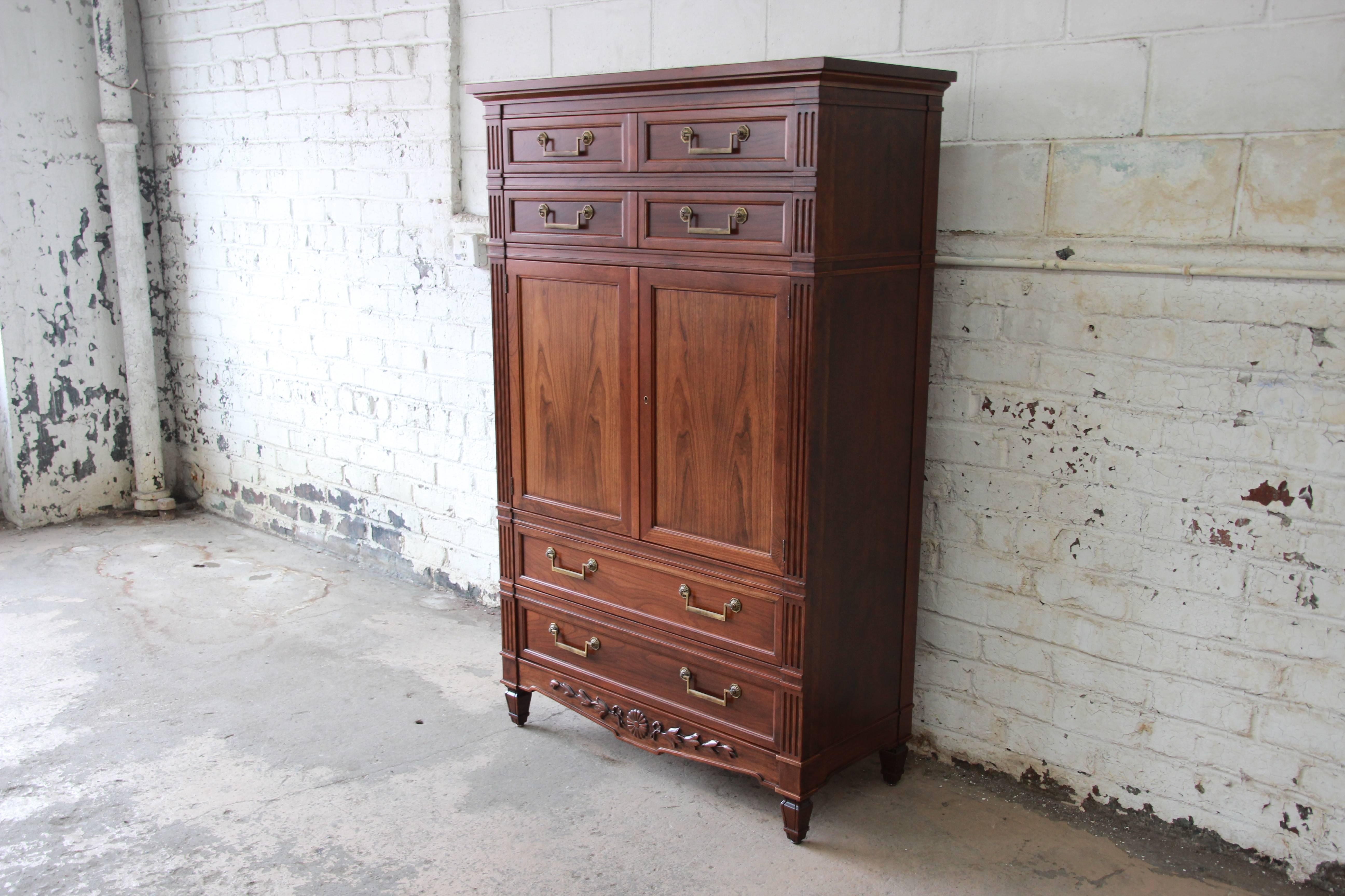 An outstanding vintage French Regency style solid cheerywood armoire or chest of drawers by Baker Furniture. The chest features gorgeous cheerywood grain with beautiful carved wood details. It offers ample room for storage, with nine dovetailed