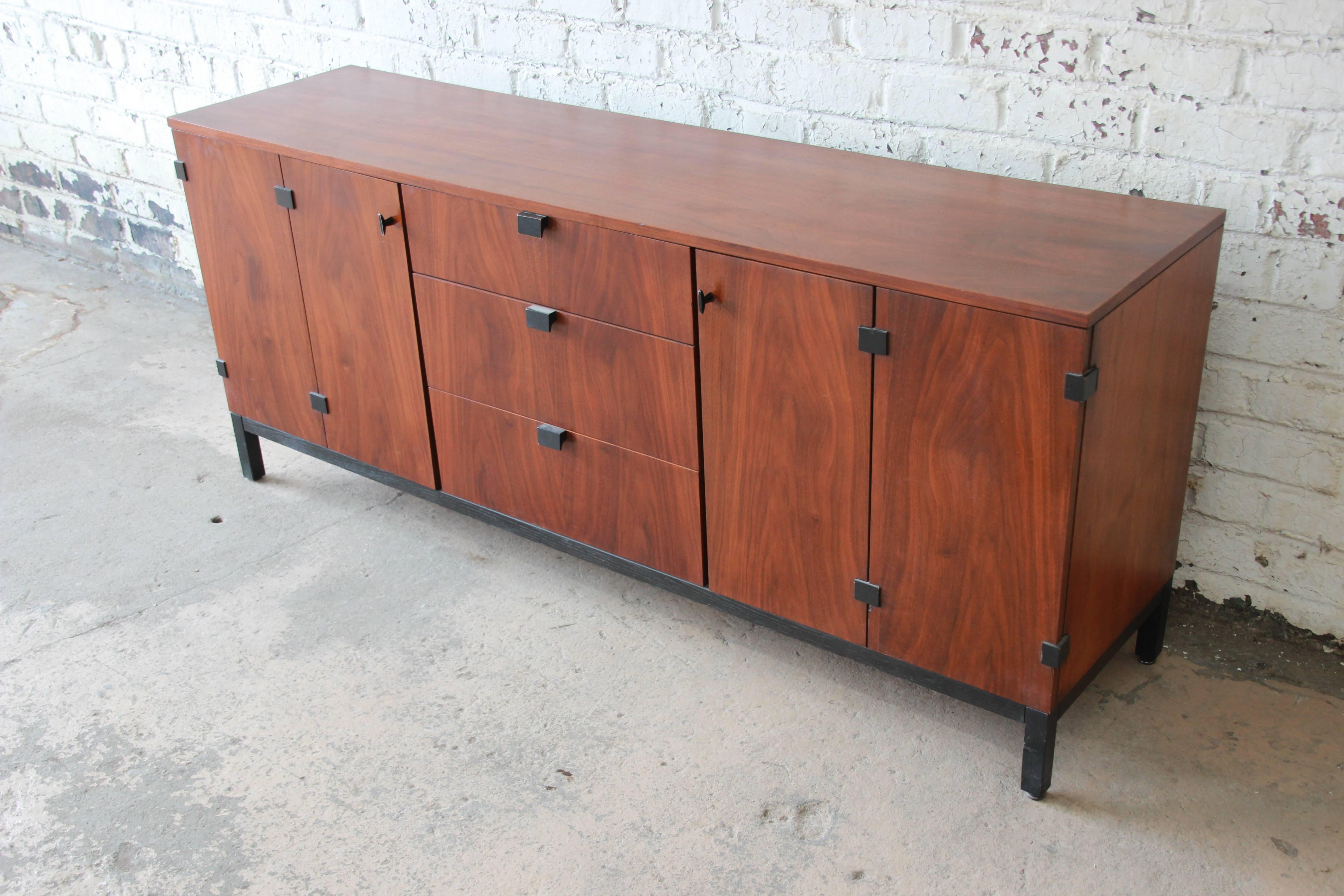 A stunning Mid-Century Modern walnut nine-drawer credenza or triple dresser designed by Kipp Stewart for Directional, circa 1960s. The credenza features gorgeous book-matched walnut wood grain, with sculpted ebonized pulls and an ebonized base. It
