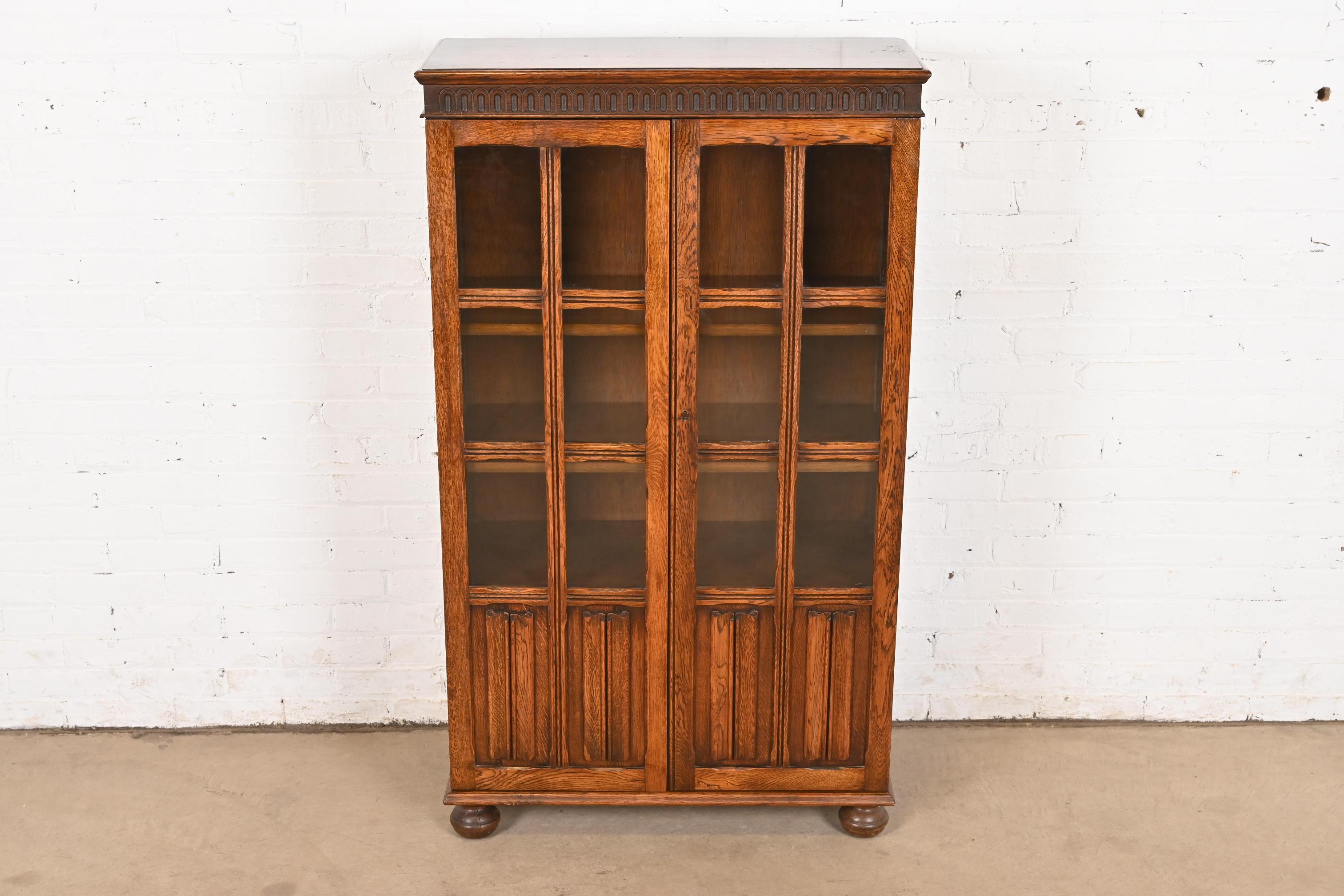 Anglais Ancienne armoire bibliothèque à façade vitrée en Oak Oak Tudor sculpté, vers 1920 en vente