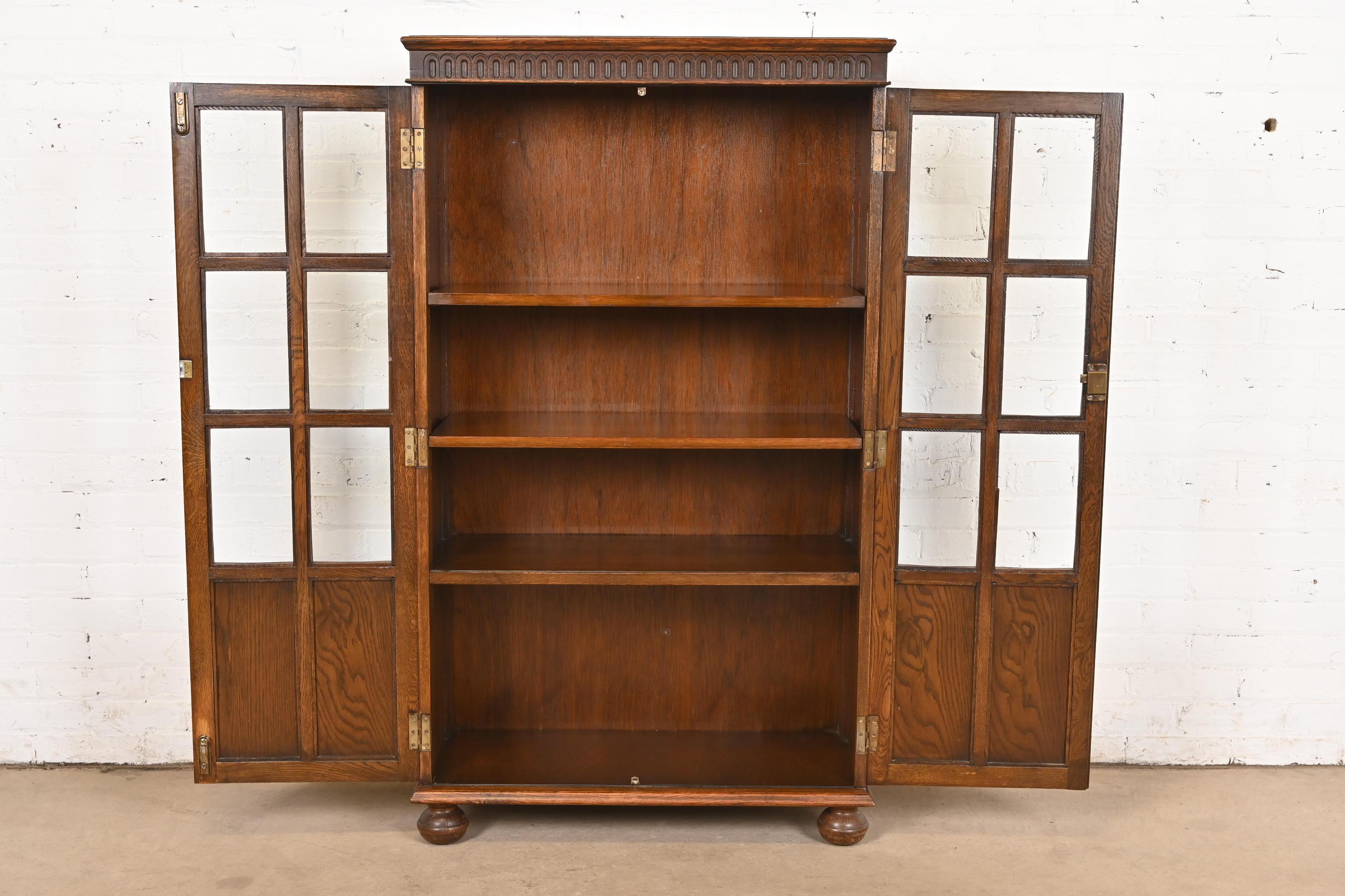 Verre Ancienne armoire bibliothèque à façade vitrée en Oak Oak Tudor sculpté, vers 1920 en vente