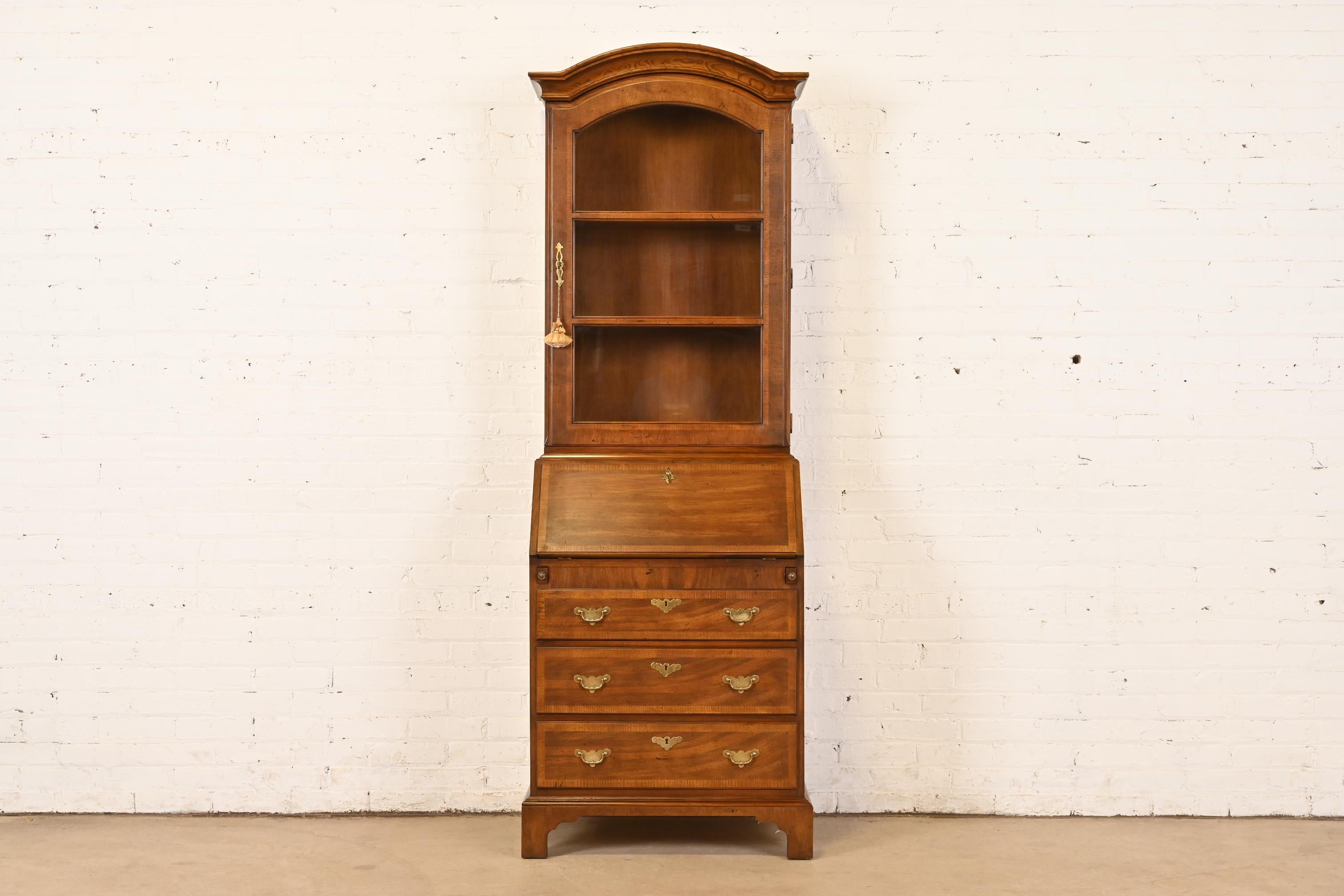 A beautiful Georgian or Queen Anne style bureau with drop front secretary desk and bookcase hutch top

By Henredon

USA, Circa 1980s

Gorgeous banded oak, with glass front bookcase hutch, and original brass hardware.

Measures: 28