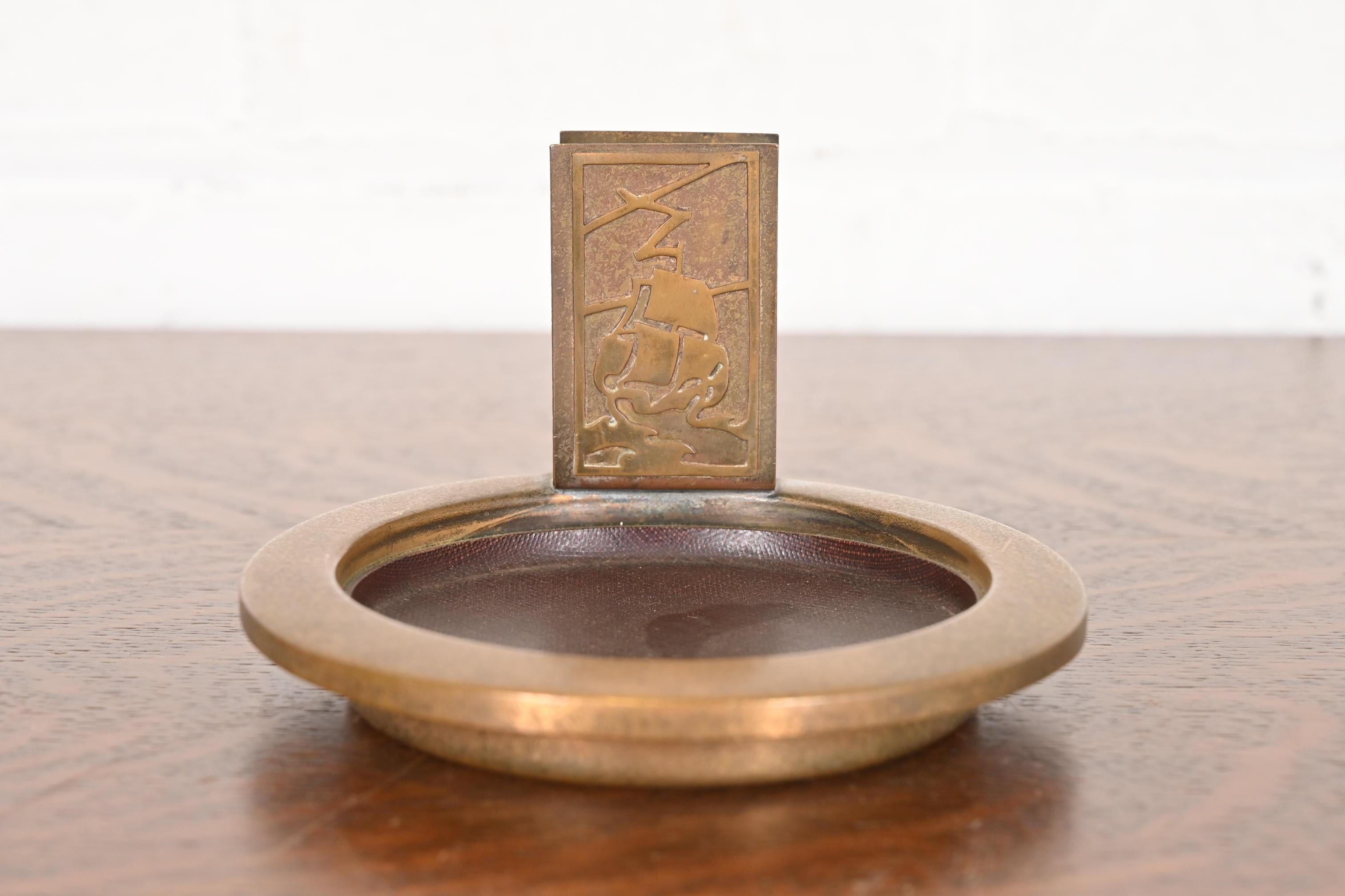 Magnifique cendrier en bronze doré d'époque Arts & Crafts avec porte-allumettes.

Par Silver Crest (la marque de Smith Metal Arts Co.), une filiale de Heintz Art Metal Shop.

États-Unis d'Amérique, début du 20e siècle

Mesures : 5,5 