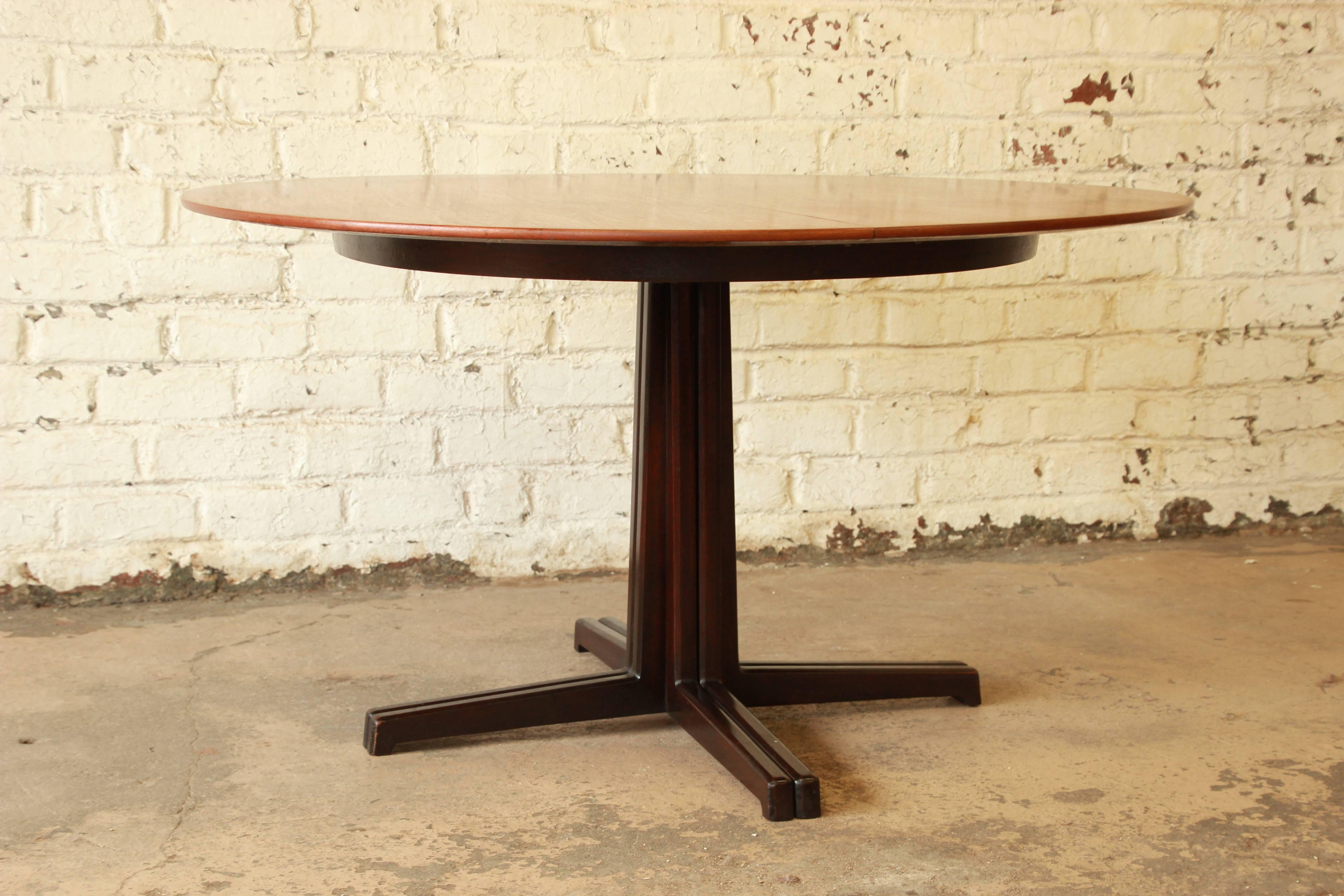 A gorgeous sculptural extension dining table in walnut designed by Edward Wormley for Dunbar, circa 1950s. Classic Wormley design, with clean, sleek Mid-Century Modern lines. It features a nicely grained walnut top with a solid walnut base. The