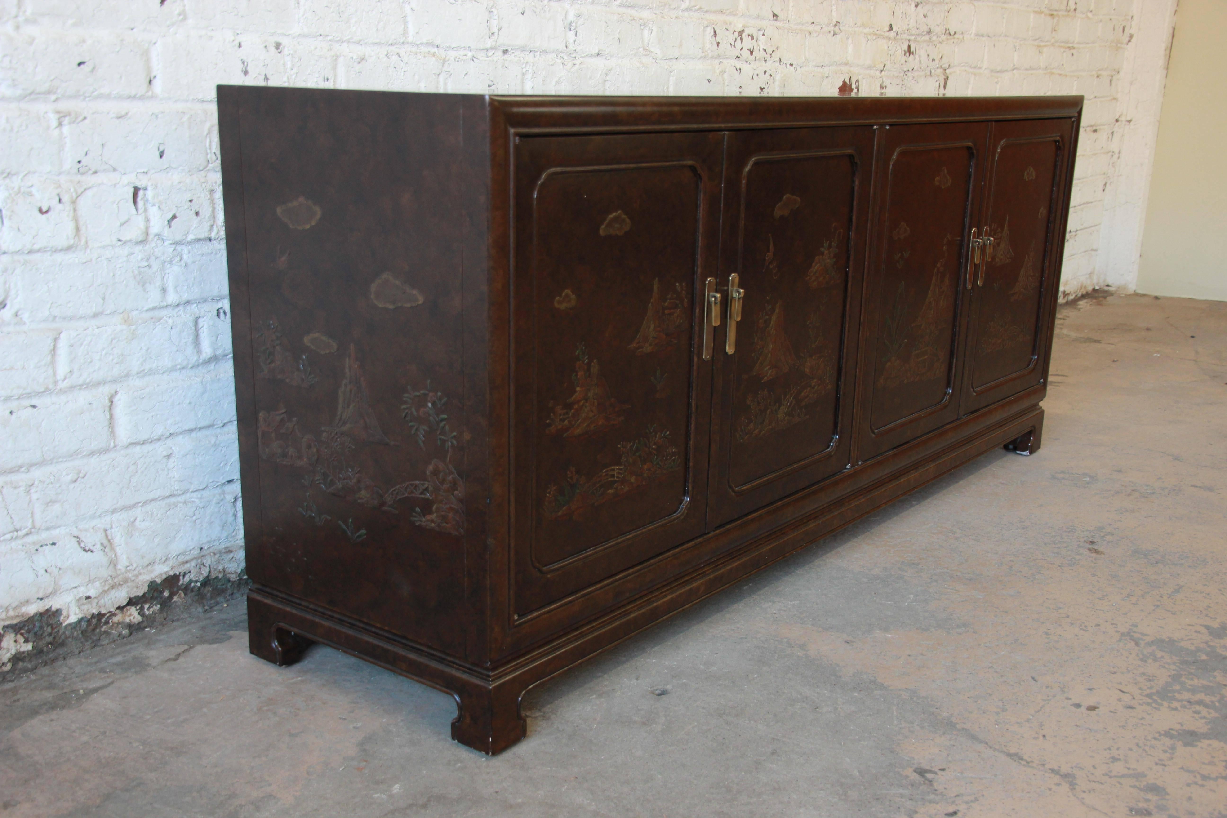 An outstanding custom chinoiserie sideboard buffet designed in 1980 by Mario Buatta for John Widdicomb. The sideboard features a beautiful faux tortoise shell finish and ornate carved landscape scenes on the front and sides of the cabinet. It offers