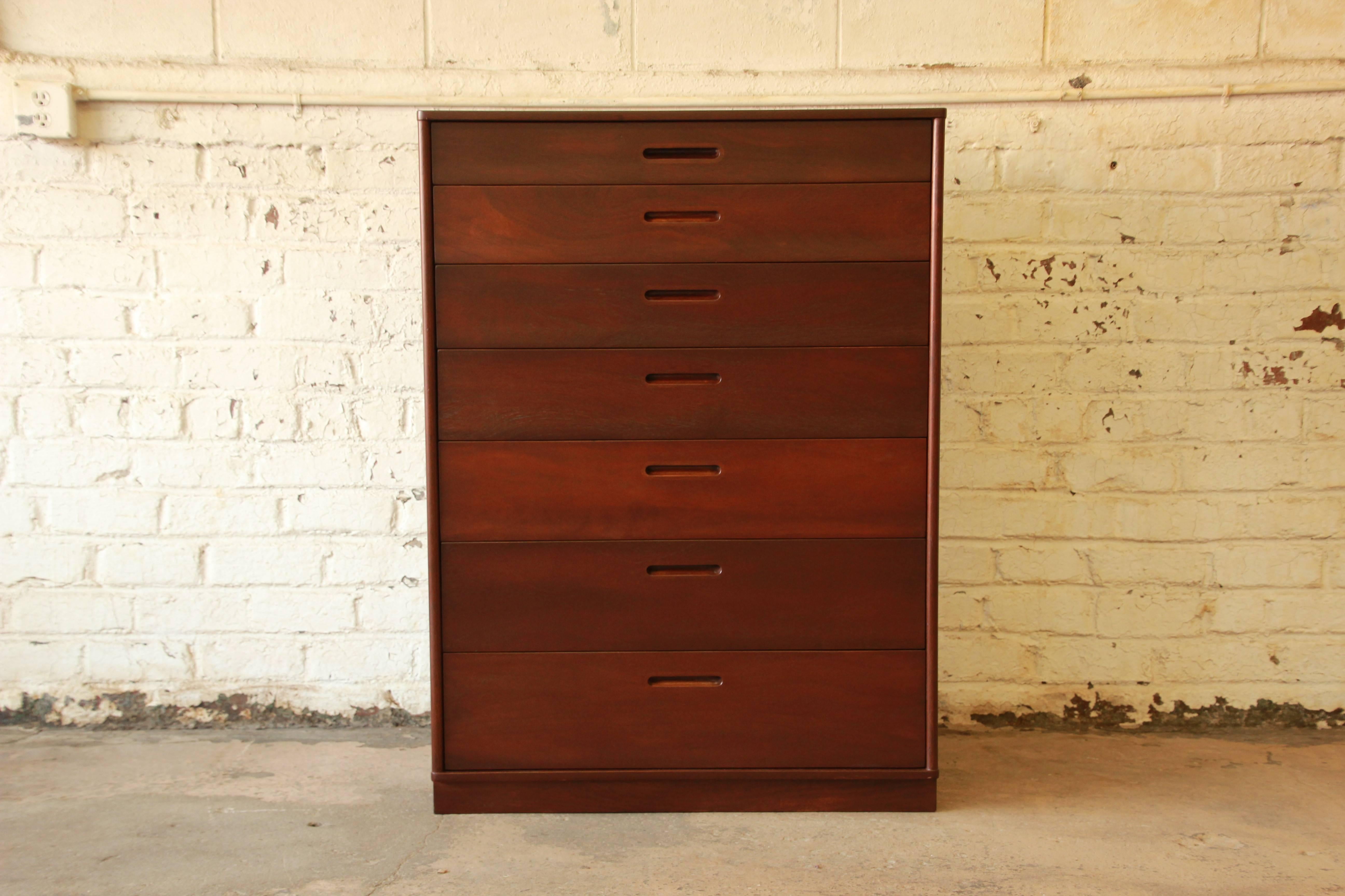 A rare and beautiful mahogany Mid-Century Modern tallboy dresser designed by Edward Wormley for Dunbar. The dresser features stunning mahogany wood grain and a sleek, Minimalist design. It offers ample room for storage with seven graduated drawers,