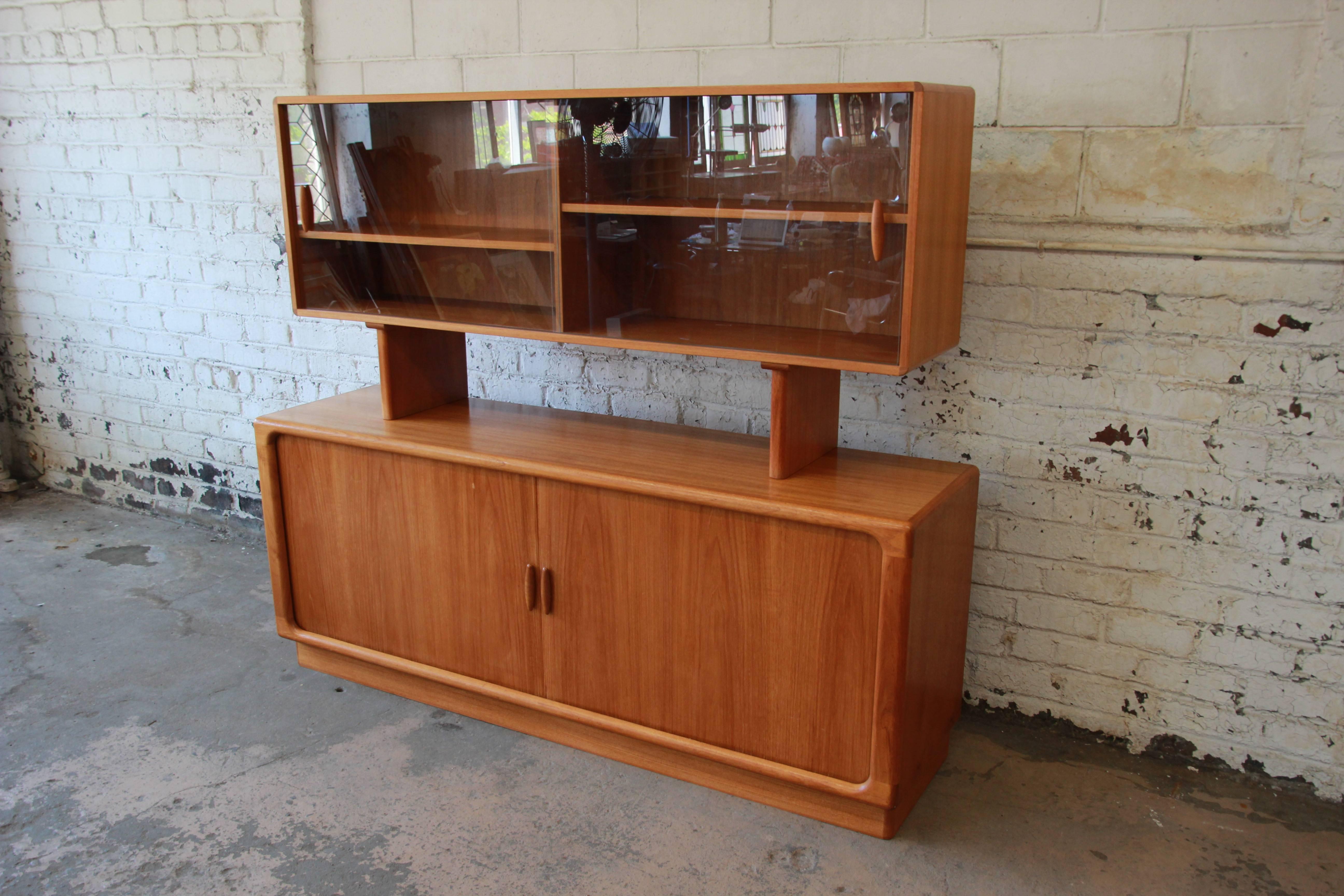 Vintage Danish modern teak credenza with glass-front top by Dyrlund. The long credenza has tambour doors that open up to five dovetailed drawers in the center. The right side has two adjustable shelves and the left a single adjustable shelf. The top