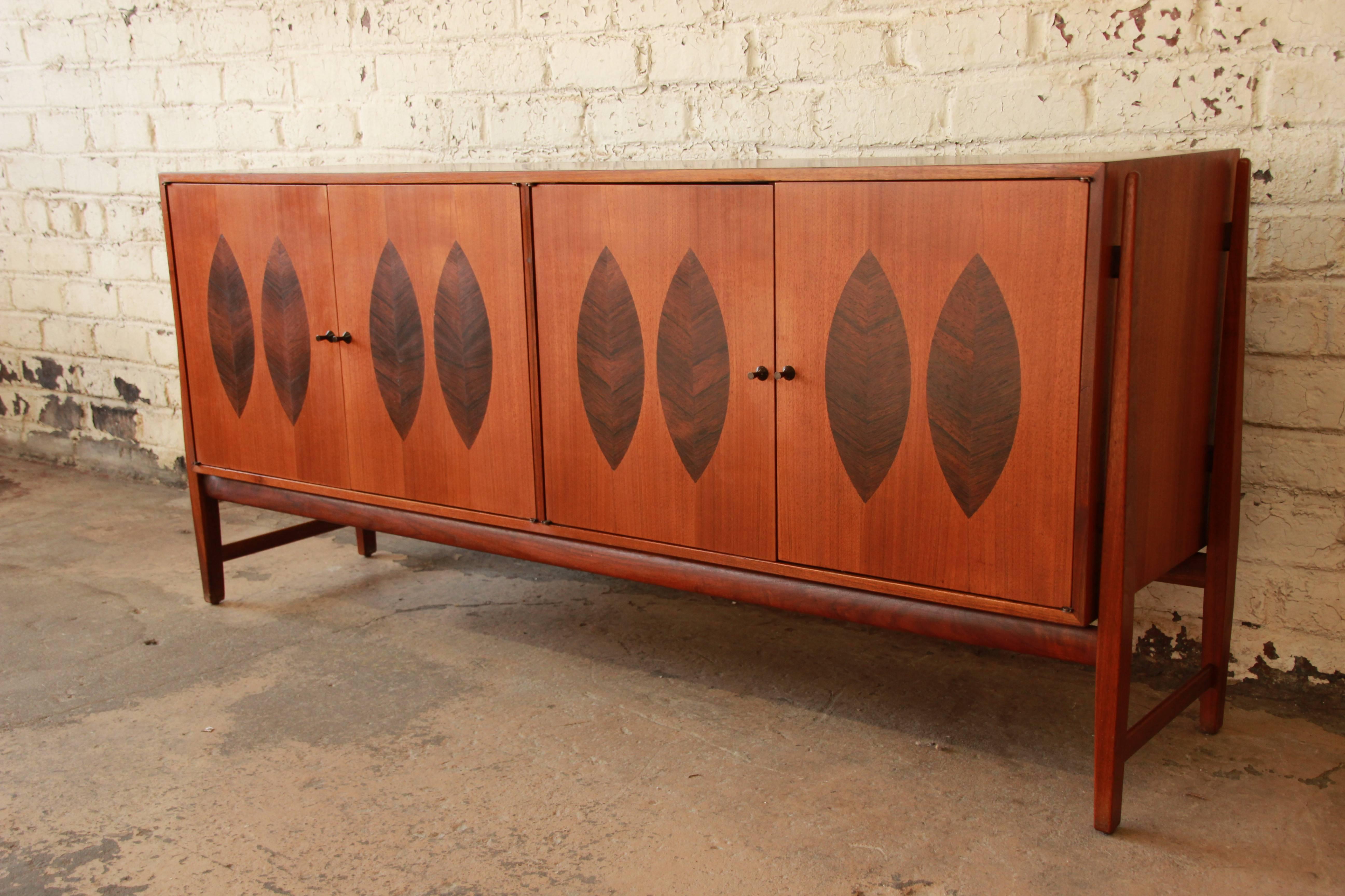 A stunning Mid-Century Modern walnut and inlaid rosewood credenza or sideboard designed by Kipp Stewart for Calvin Furniture. This rare credenza was produced for Calvin's American Design Foundation line, circa 1960. The four-door cabinet features an