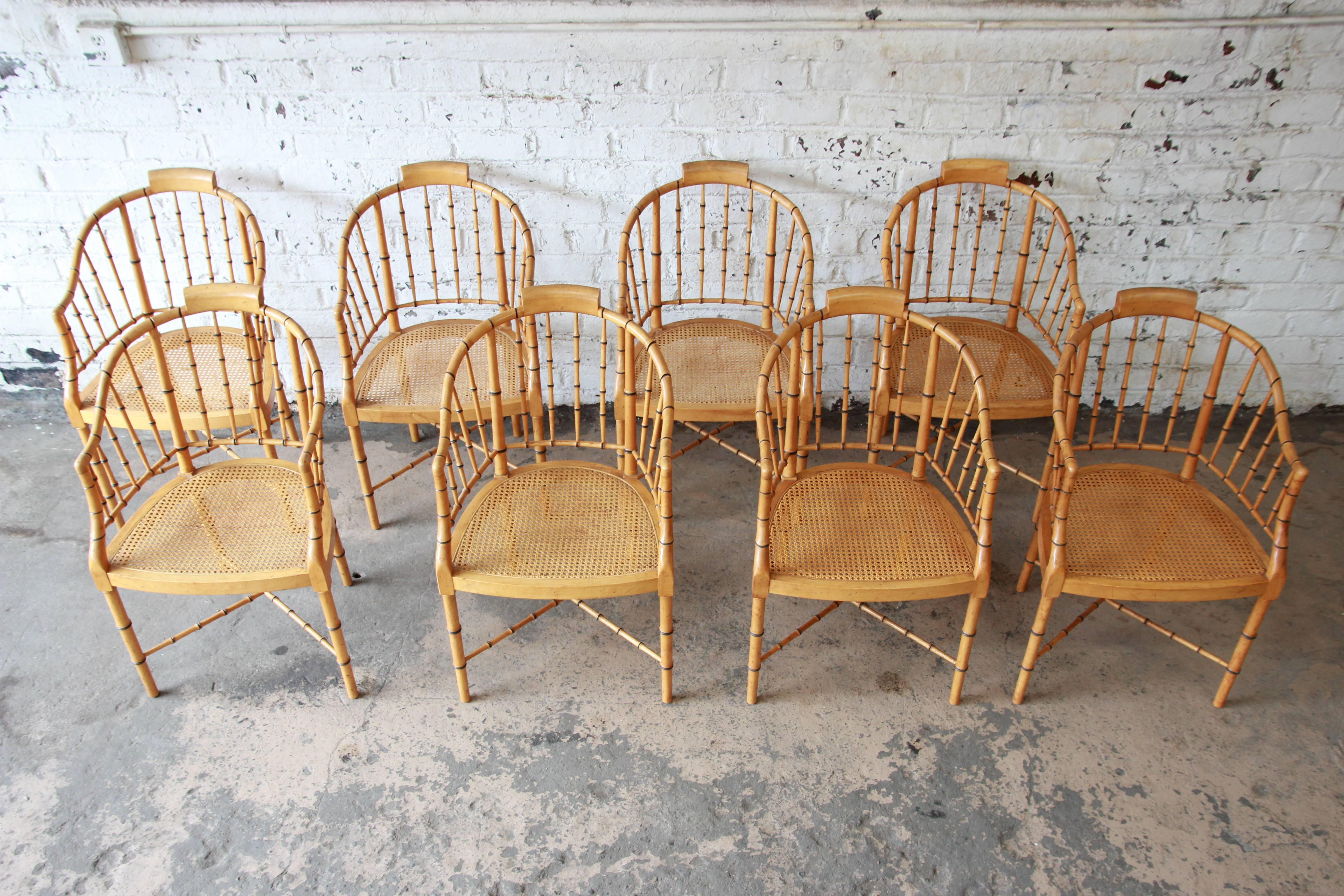 Outstanding Regency bamboo chairs produced by Baker Furniture, circa 1960. The chairs feature tub-shaped backs and cane seats. They are raised on four slender legs, connected to each other through an X-shaped cross stretcher. The original of the