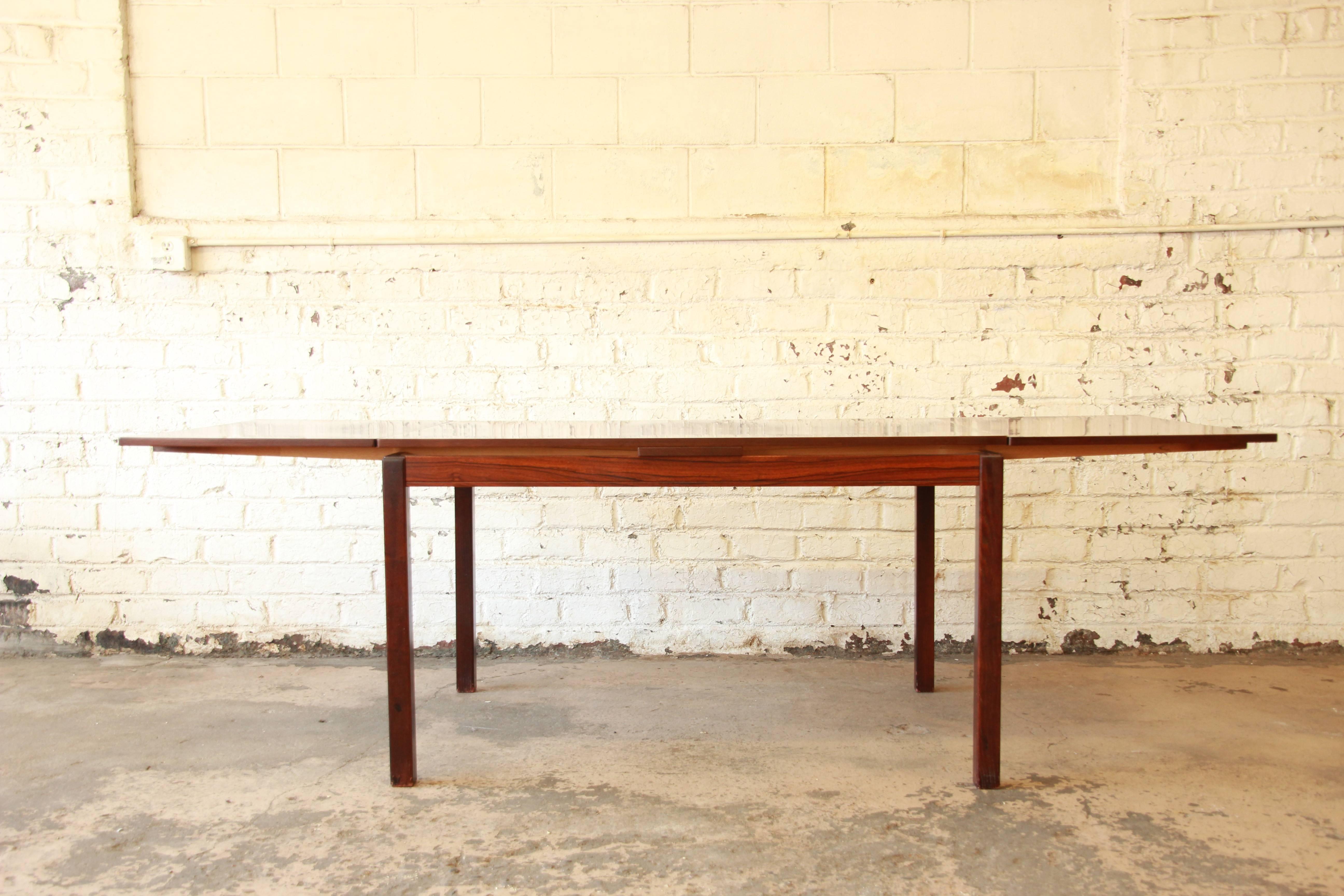 A stunning Norwegian rosewood extension dining table produced by Heggen, circa 1960s. The table features gorgeous wood grain and sleek Scandinavian Modern design. It is sturdy and well made. The table has built-in leaves that nearly double the