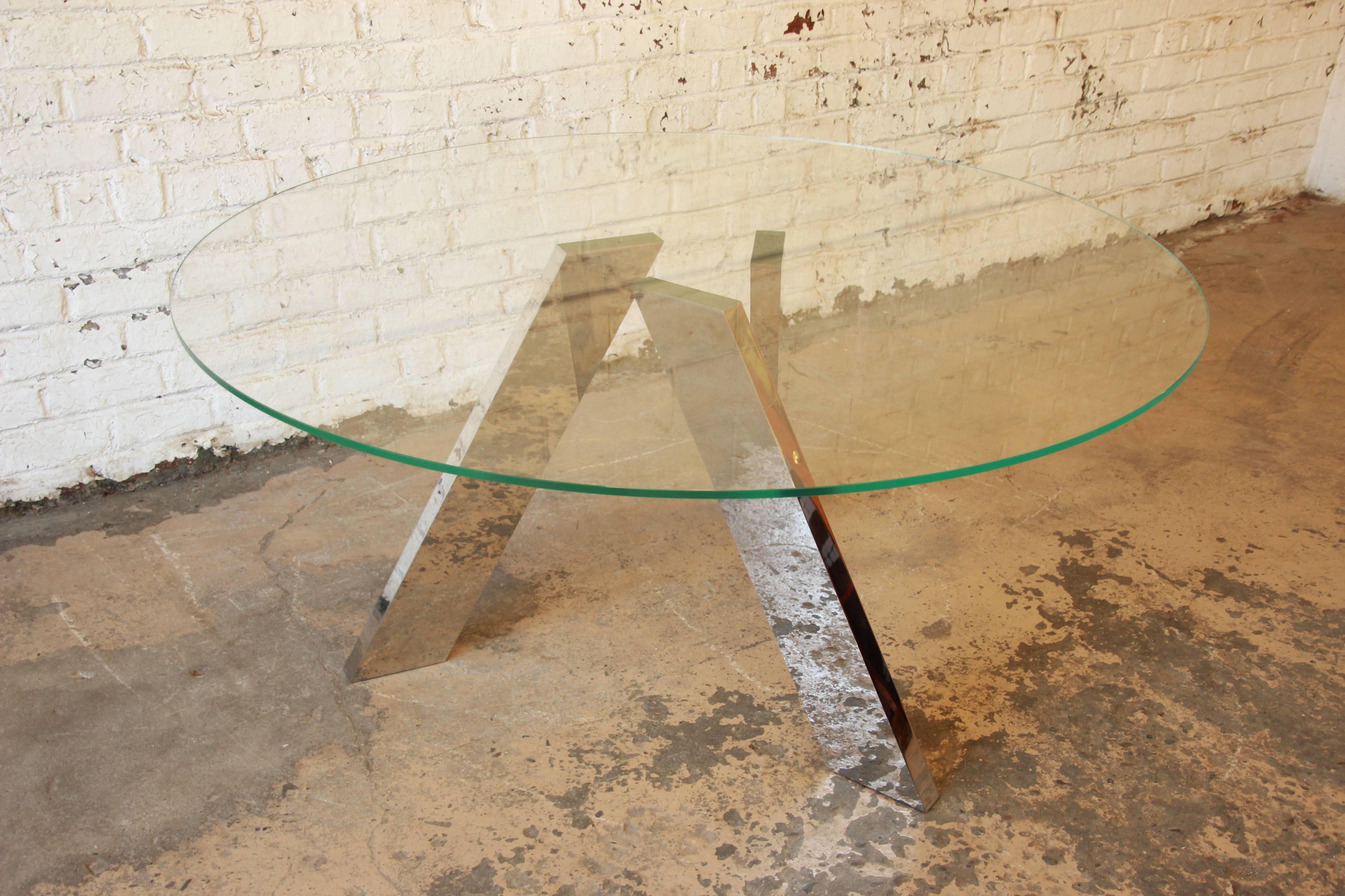 A beautifully designed modern dining table by Roche Bobois, circa 1980s. The table features a thick round glass top and mirrored chrome legs that are detachable. It can seat up to eight chairs comfortably. Great architectural design. The table is in