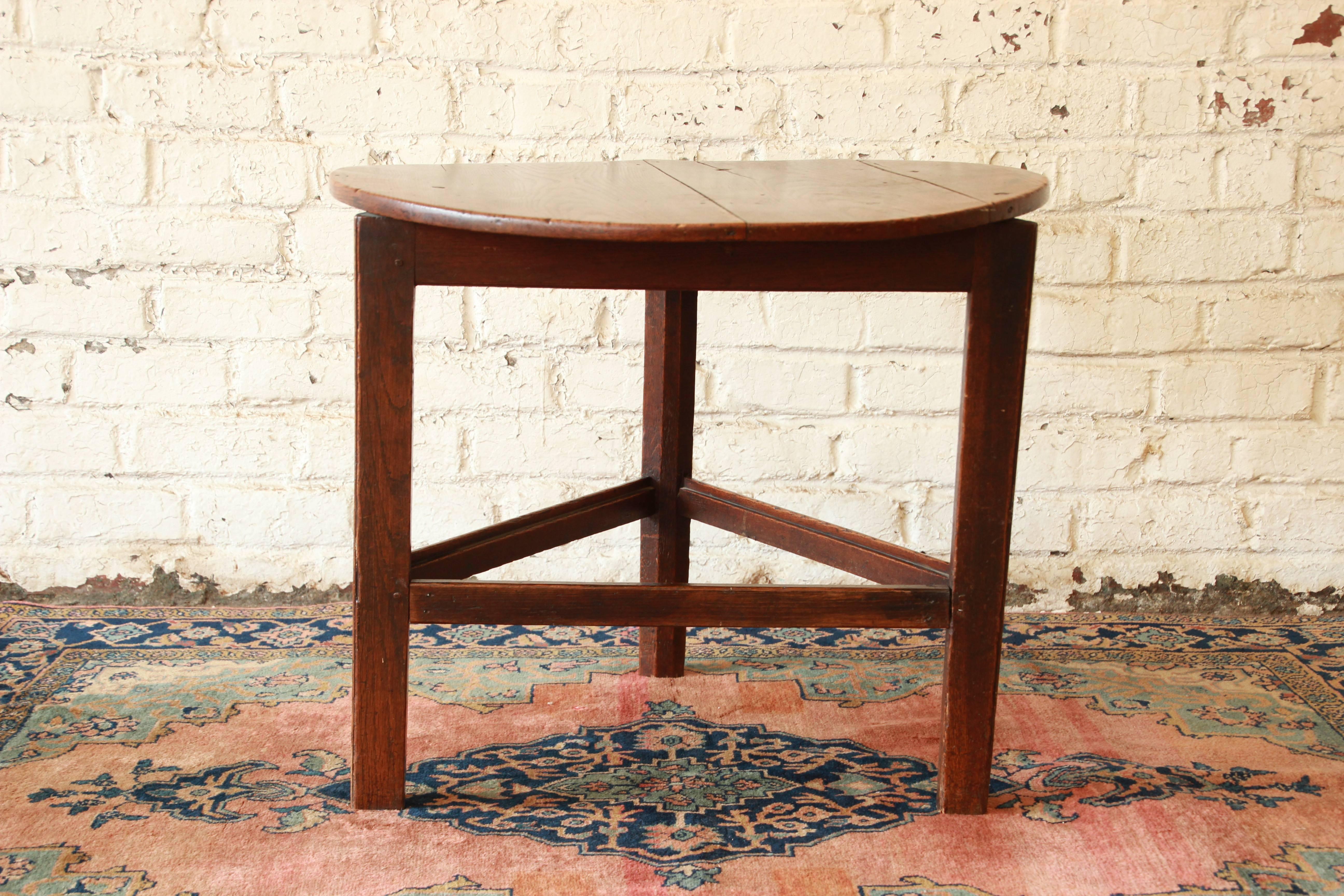 A very rare and unique 18th century English oak tavern table. The table features an original rustic oak finish. It has a round top and a triangle base. The table is well built from solid oak. The top has some cracks in it and bows slightly upward
