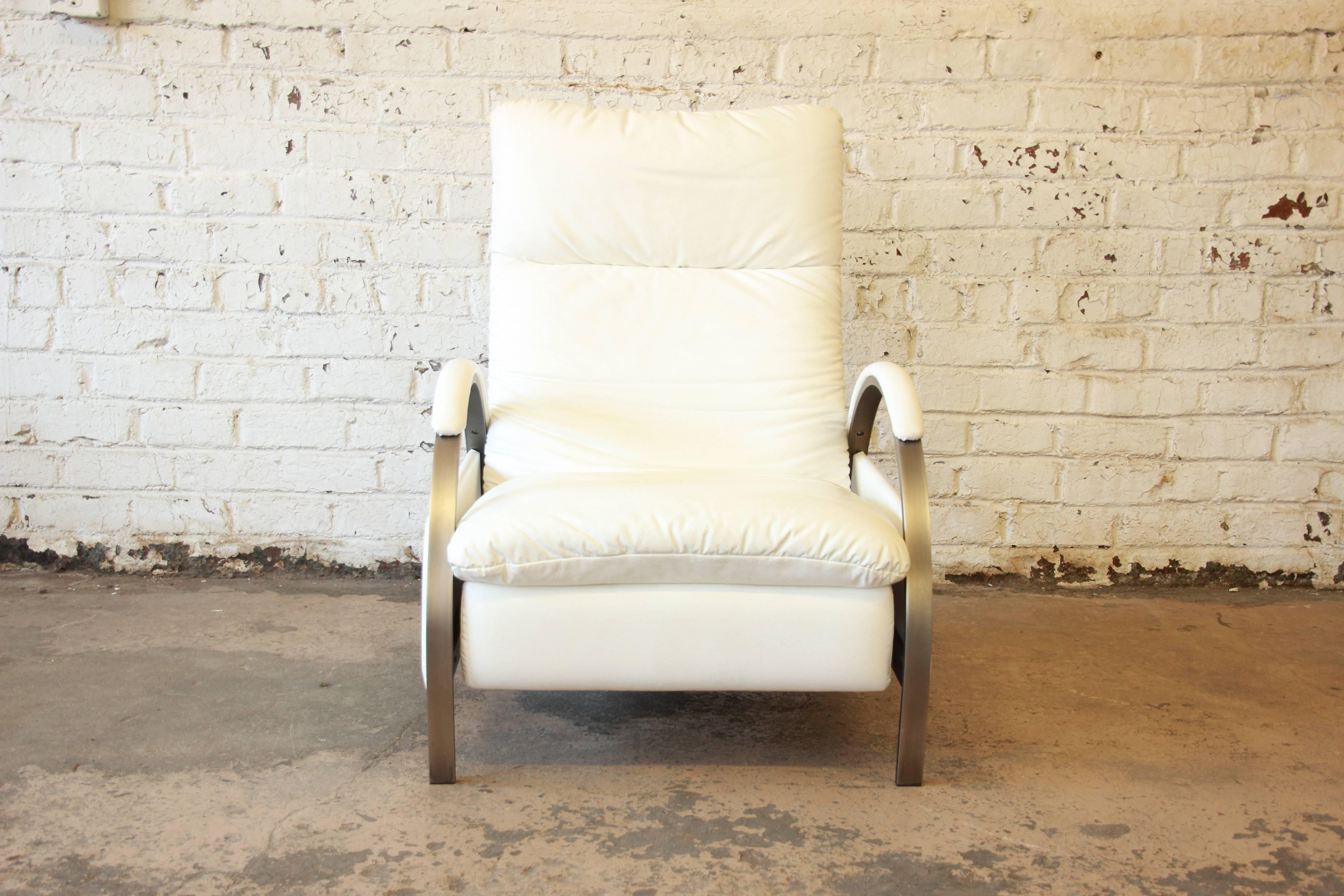 A gorgeous reclining leather lounge chair designed by George Mulhauser for the Design Institute of America. The recliner features a unique design with curved brushed chrome legs/armrests and white leather that is clean and in good condition. The