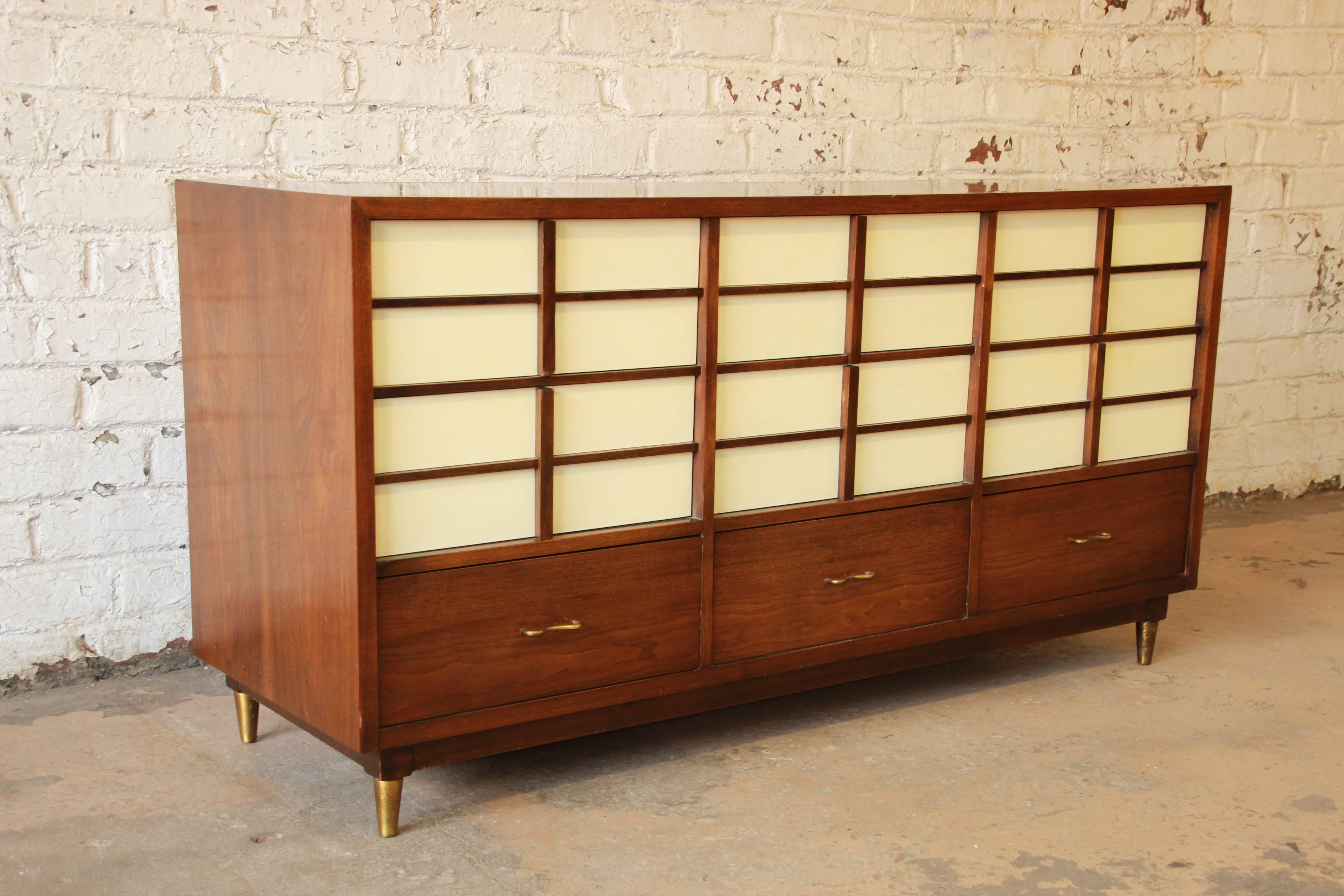 A beautiful Mid-Century Modern nine-drawer dresser or credenza designed by Merton Gershun for American of Martinsville. The dresser features sleek Mid-Century lines, gorgeous walnut wood grain, and a unique design, with white lacquered drawers. The