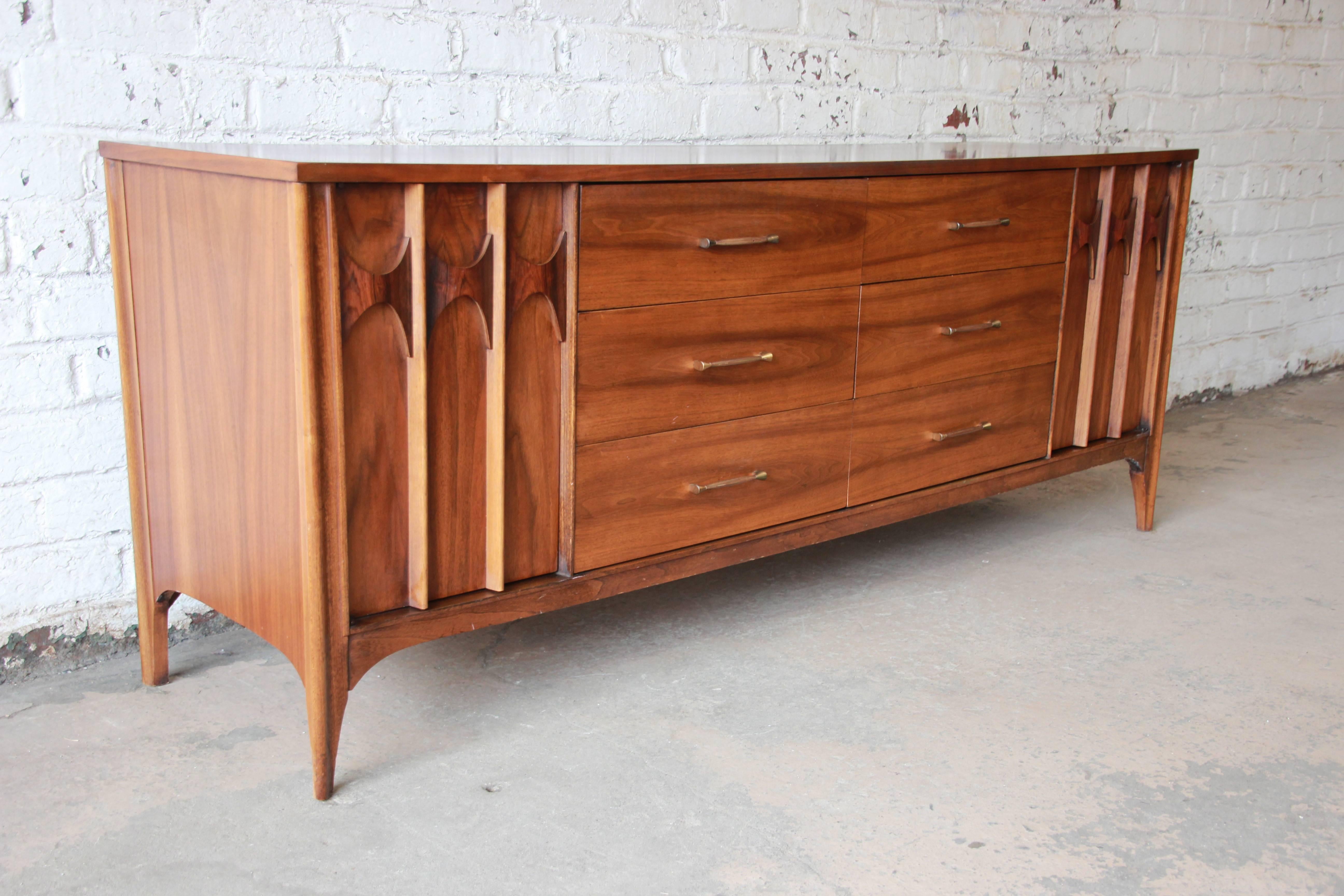 A stylish Mid-Century Modern walnut and rosewood credenza or long dresser from the Perspecta line by Kent Coffey. The credenza features stunning wood grain and sleek Mid-Century lines. Each door has beautiful sculpted wood details, and there are