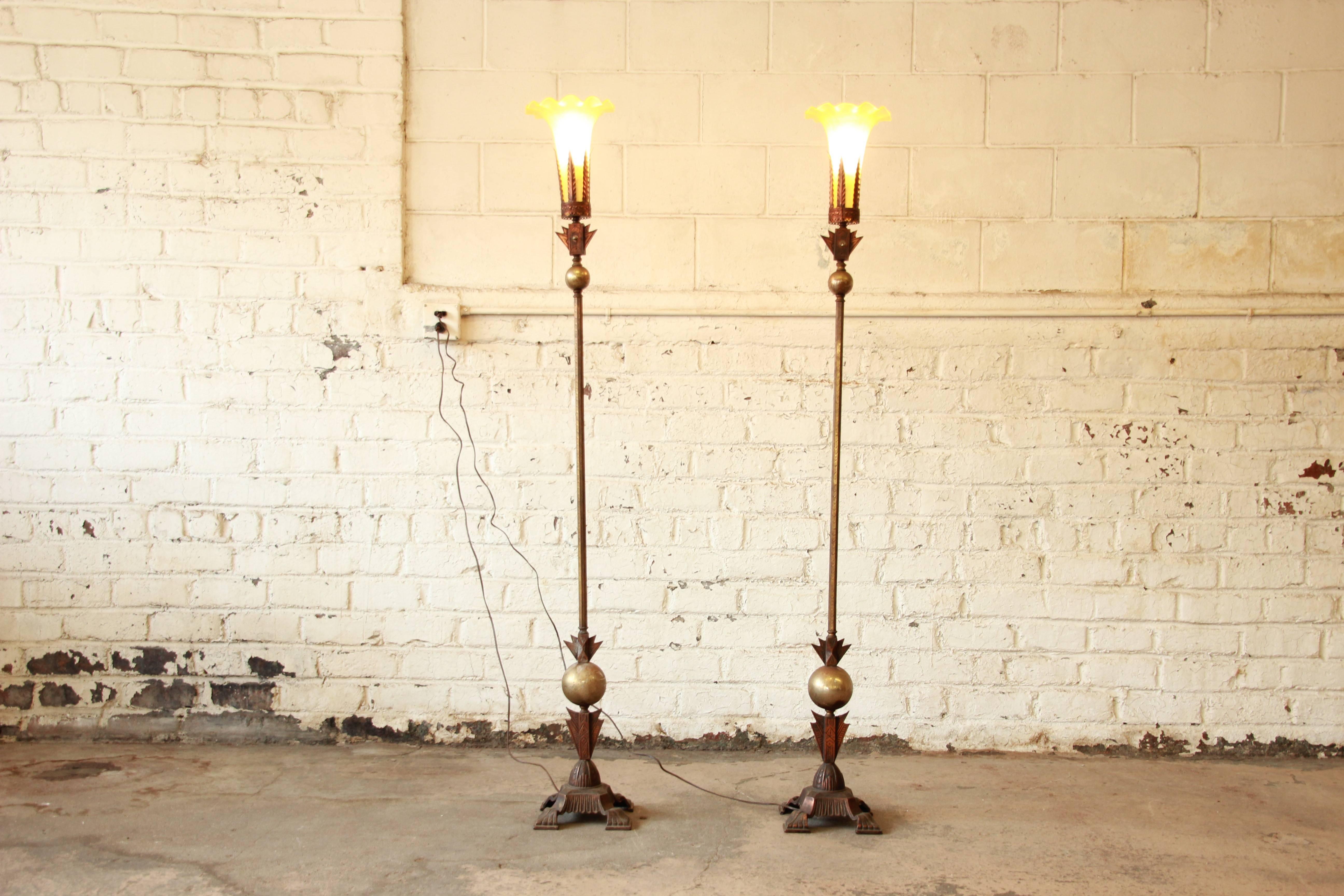 A gorgeous pair of French Art Deco period brass torchiere floor lamps with blown glass shades. The lamps have a unique and unusual design with stunning details. The brass has a nice patina consistent with age. The lamps are in excellent working