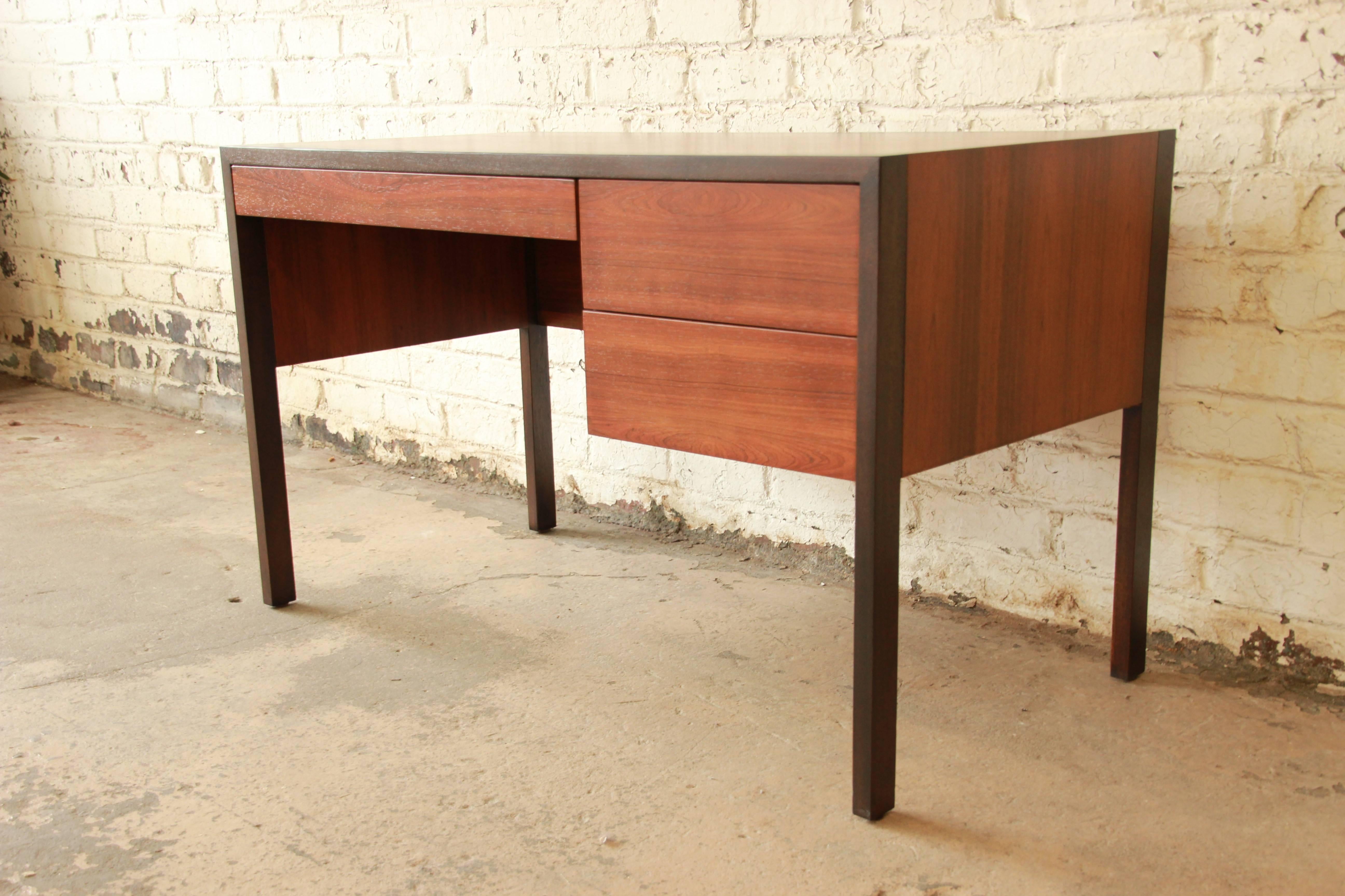 An exceptional Mid-Century Modern desk by iconic designer Harvey Probber. The desk features beautiful rosewood grain, with dark lacquered trim and legs. It has clean and sleek Mid-Century Modern lines--an excellent example of Probber's design work.