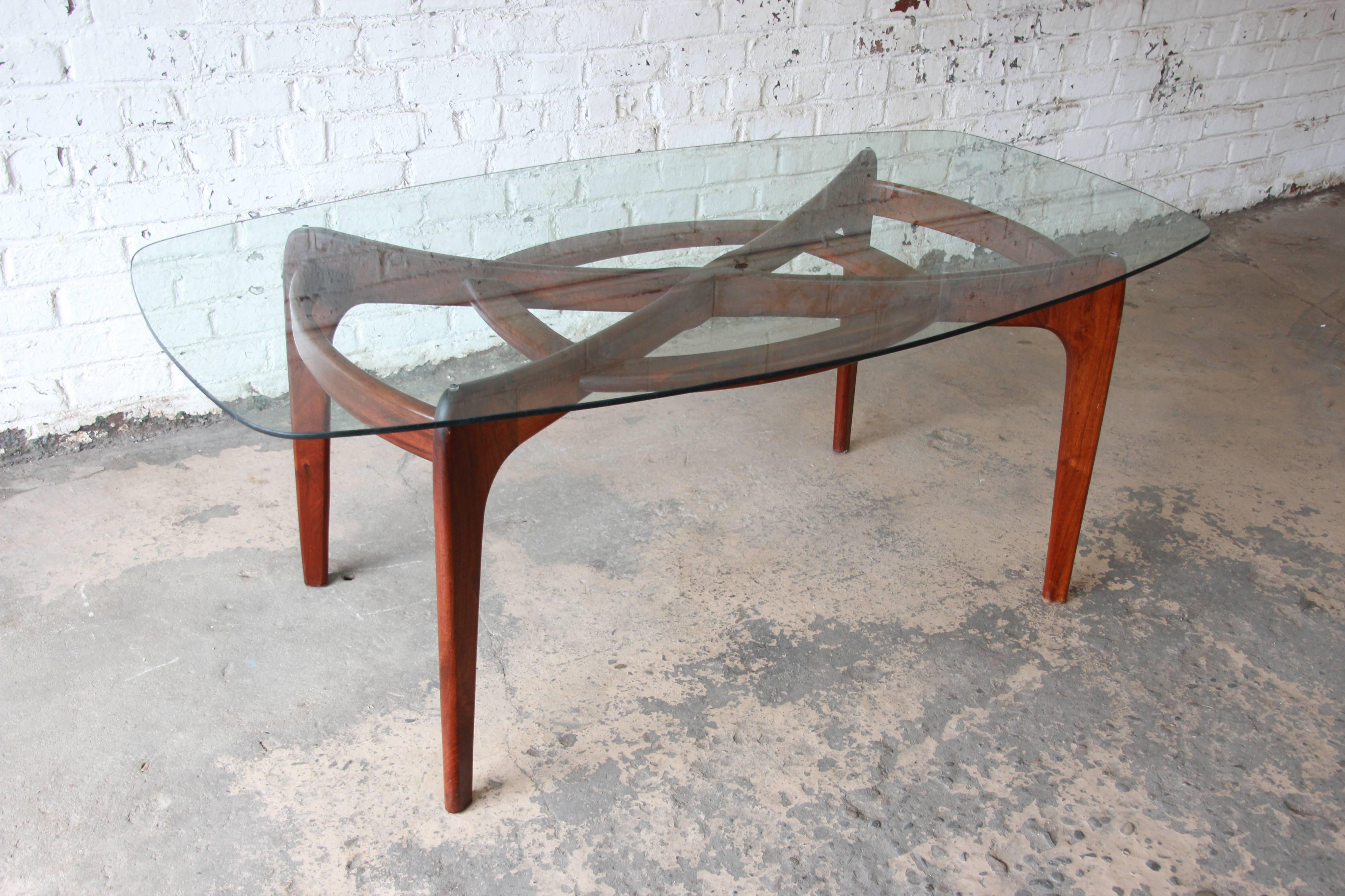 An exceptional Mid-Century Modern dining table designed by Adrian Pearsall for Craft Associates. The table features a unique sculpted solid walnut base with an elongated glass top. There are no chips or cracks in the glass. An excellent example of