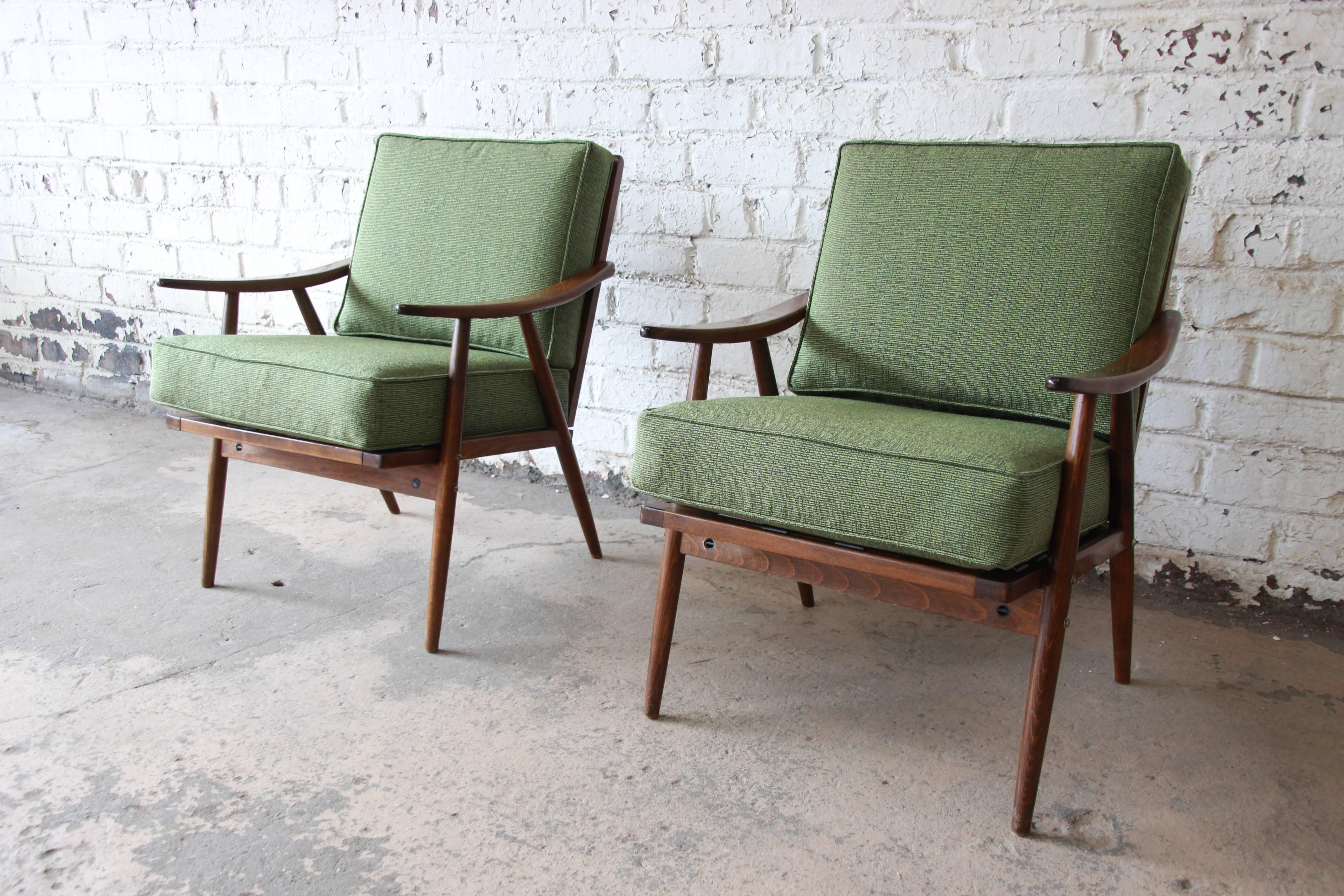An exceptional pair of Mid-Century Modern lounge chairs in the Danish Modern style. The chairs were manufactured, circa 1950 by Ligna. They feature gorgeous sculpted solid walnut frames, with sleek and stylish Mid-Century design. Recently