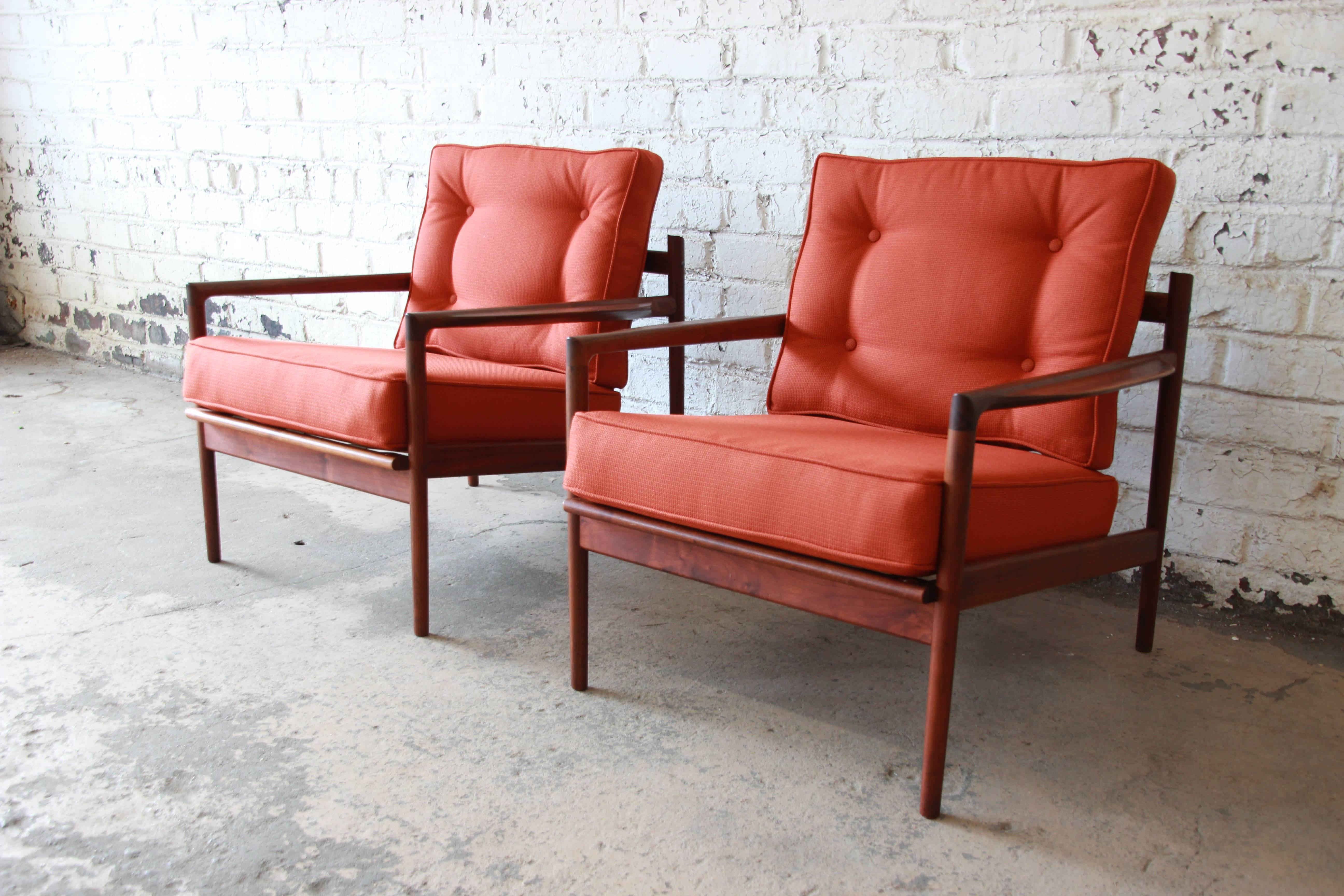 A stunning pair of Danish Modern picket back lounge chairs designed by Ib Kofod-Larsen for Selig. The chairs feature gorgeous walnut frames with a unique picket back design. They have recently been restored with new foam and designer Herman Miller