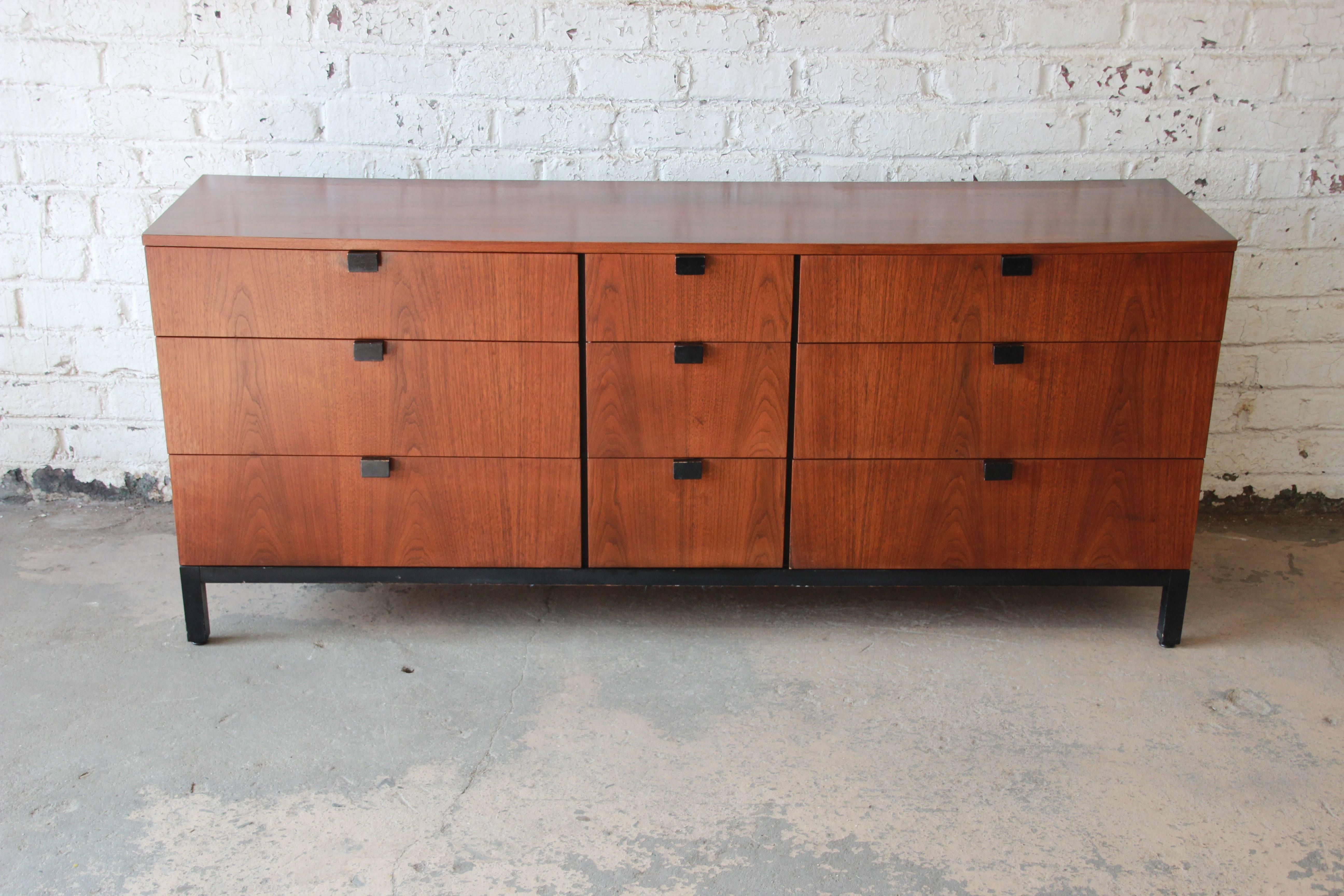 Offering a stunning Mid-Century Modern walnut nine-drawer dresser designed by Milo Baughman for Directional, circa 1960s. The dresser features gorgeous book-matched walnut wood grain, with sculpted ebonized pulls and an ebonized base. It offers