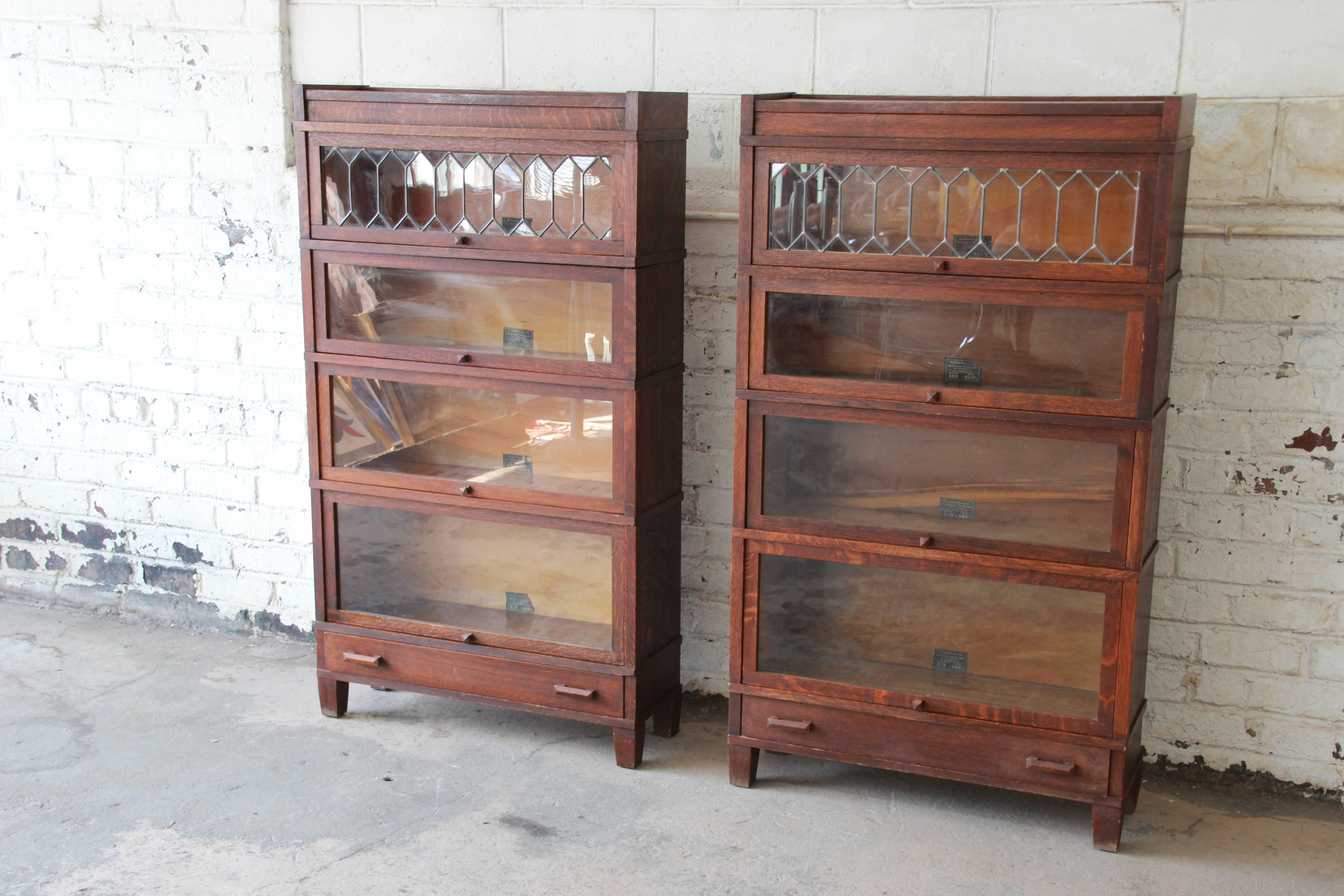 An outstanding pair of antique oak barrister bookcases by Globe-Wernicke. The bookcases feature gorgeous quarter sawn tiger oakwood grain and a nice Arts & Crafts design. The top glass door on each case has a beautiful leaded glass front with a