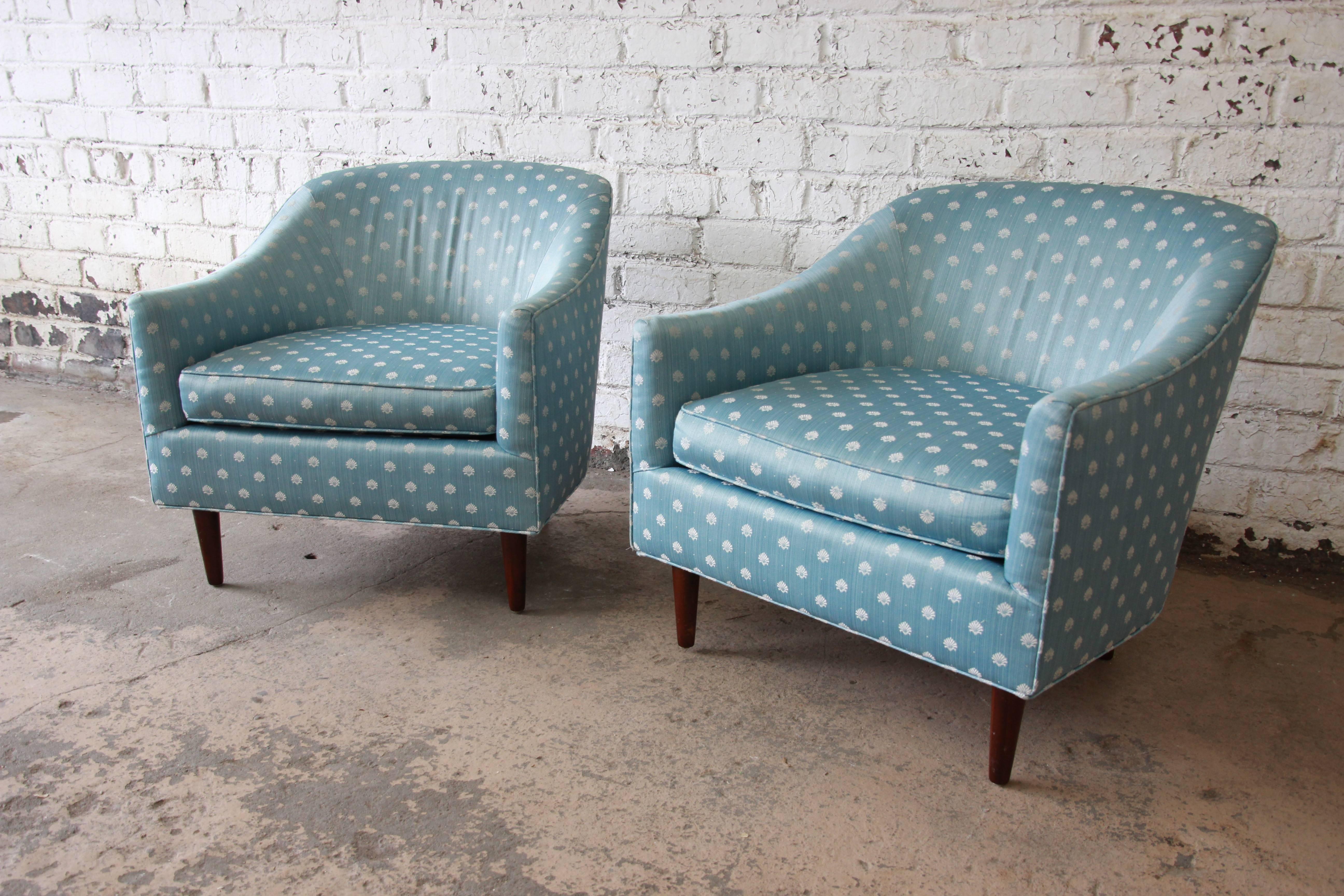 A gorgeous pair of Mid-Century Modern barrel back club chairs in the style of Milo Baughman. The chairs feature beautiful light blue and ivory upholstery and stylish solid walnut tapered legs. A very comfortable pair in good vintage