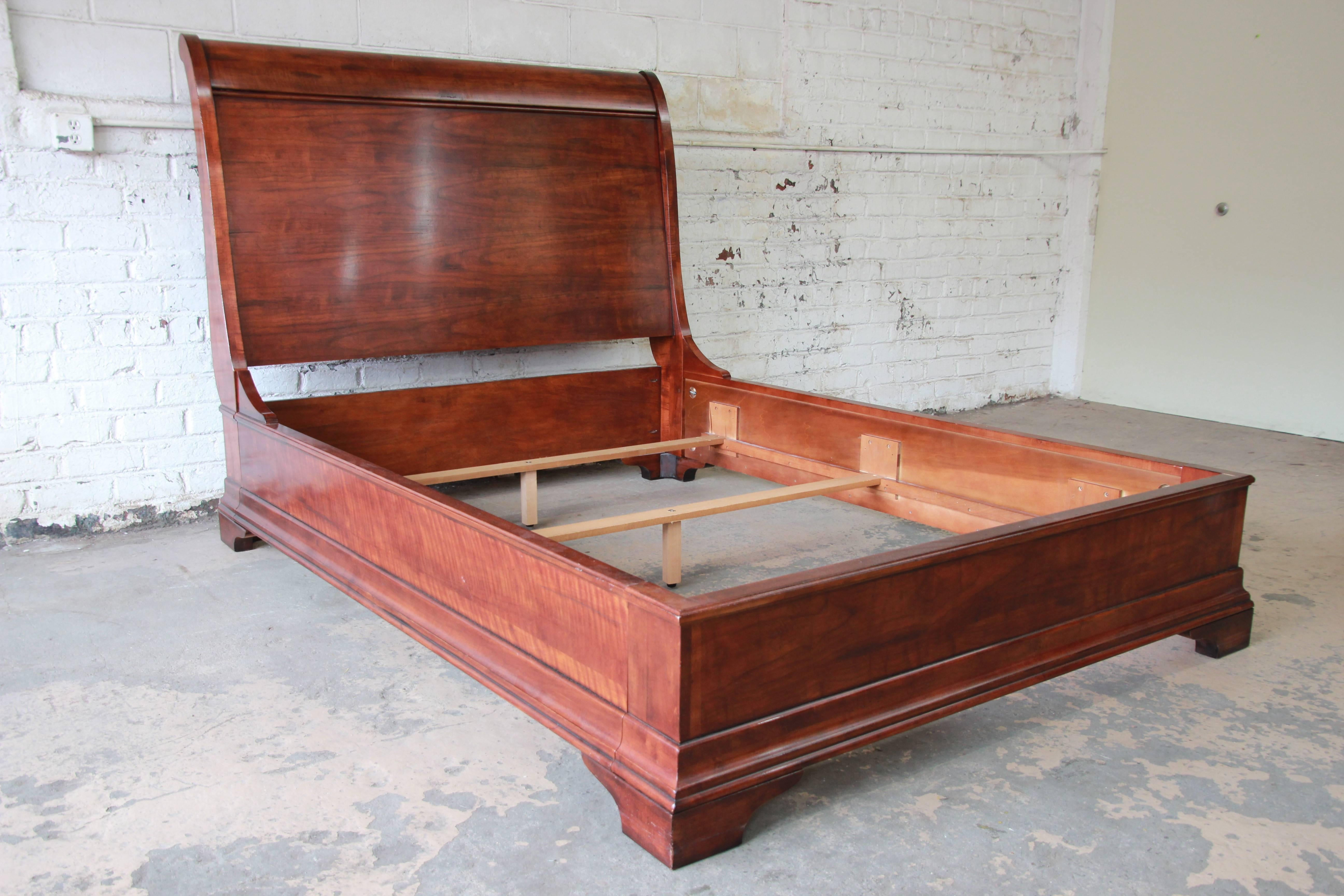 A gorgeous aged cherrywood queen-size bed frame by Henredon Fine Furniture. The bed frame features stunning wood grain and a nice traditional style. It is made with exceptional craftsmanship from solid cherry wood. Original Henredon label is