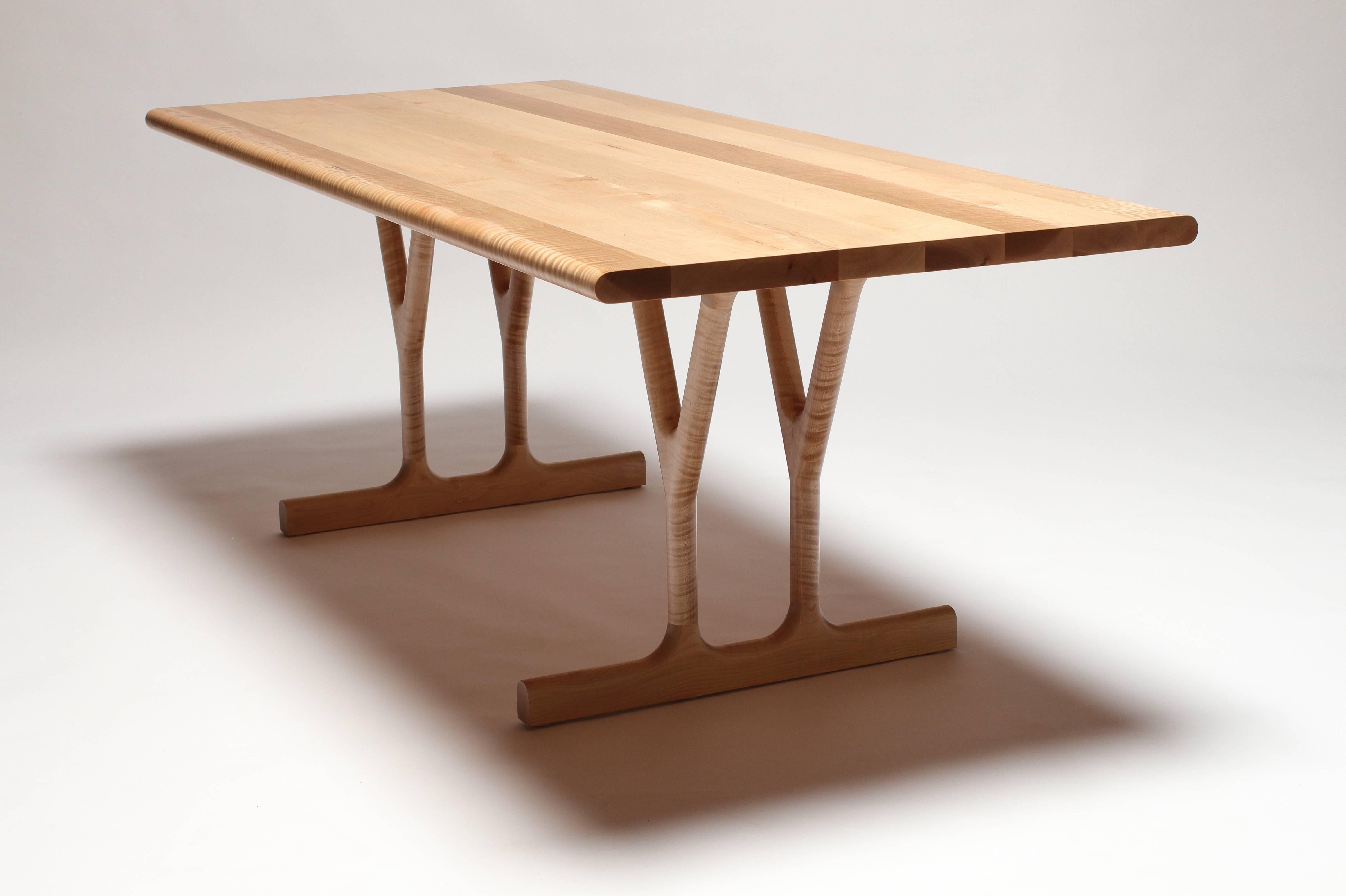 The Slingshot dining table is a solid wood table designed by Justin Godar in 2017. The slingshot-shaped legs provide a sturdy base that will not interfere with most chair placements. Each table is built in San Francisco by Justin Godar from hand