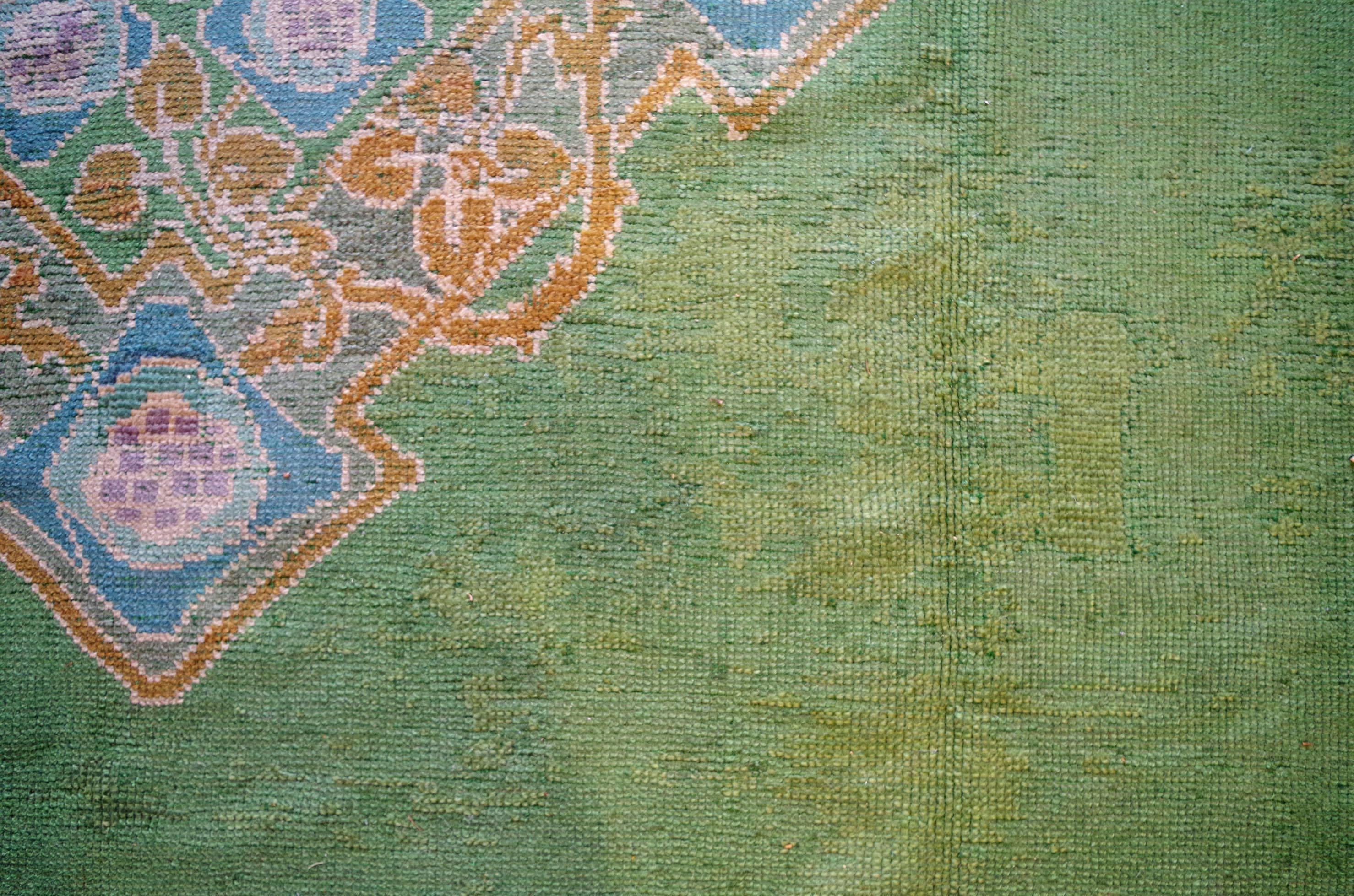 One of a suite of three Arts & Crafts carpets. Woven in Donegal, Ireland, circa 1890. A border of sinuous tendrils around a lattice with stylized floral motifs forms the border and central medallion; set upon the favoured green of this period.
