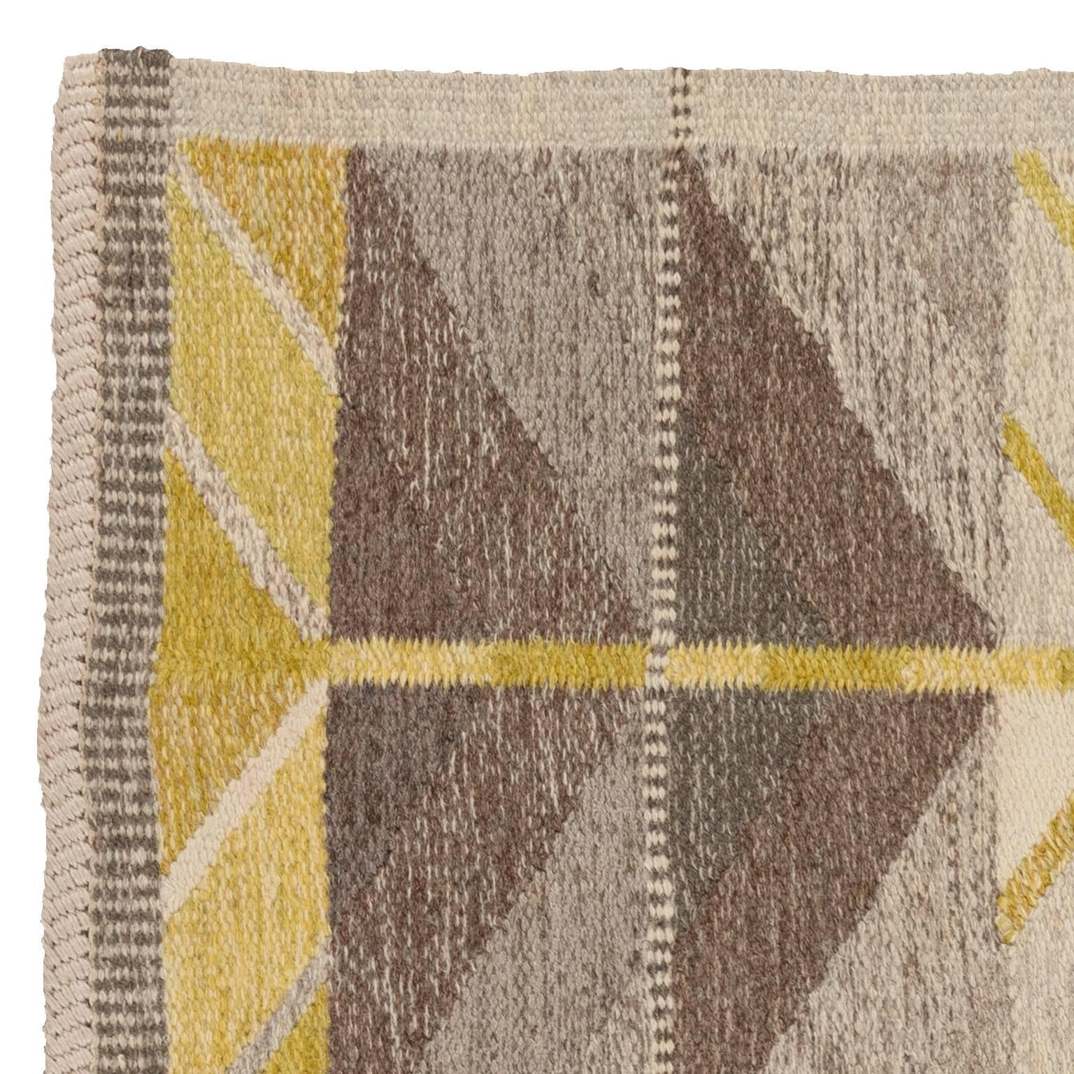 This iconic vintage Swedish flat-weave rug designed by Ingrid Dessau (1923-2000) features an all-over design of geometric shapes and lines in varying shades of grey, with yellow accents. The rug is a handwoven art-piece and always modern. Excellent